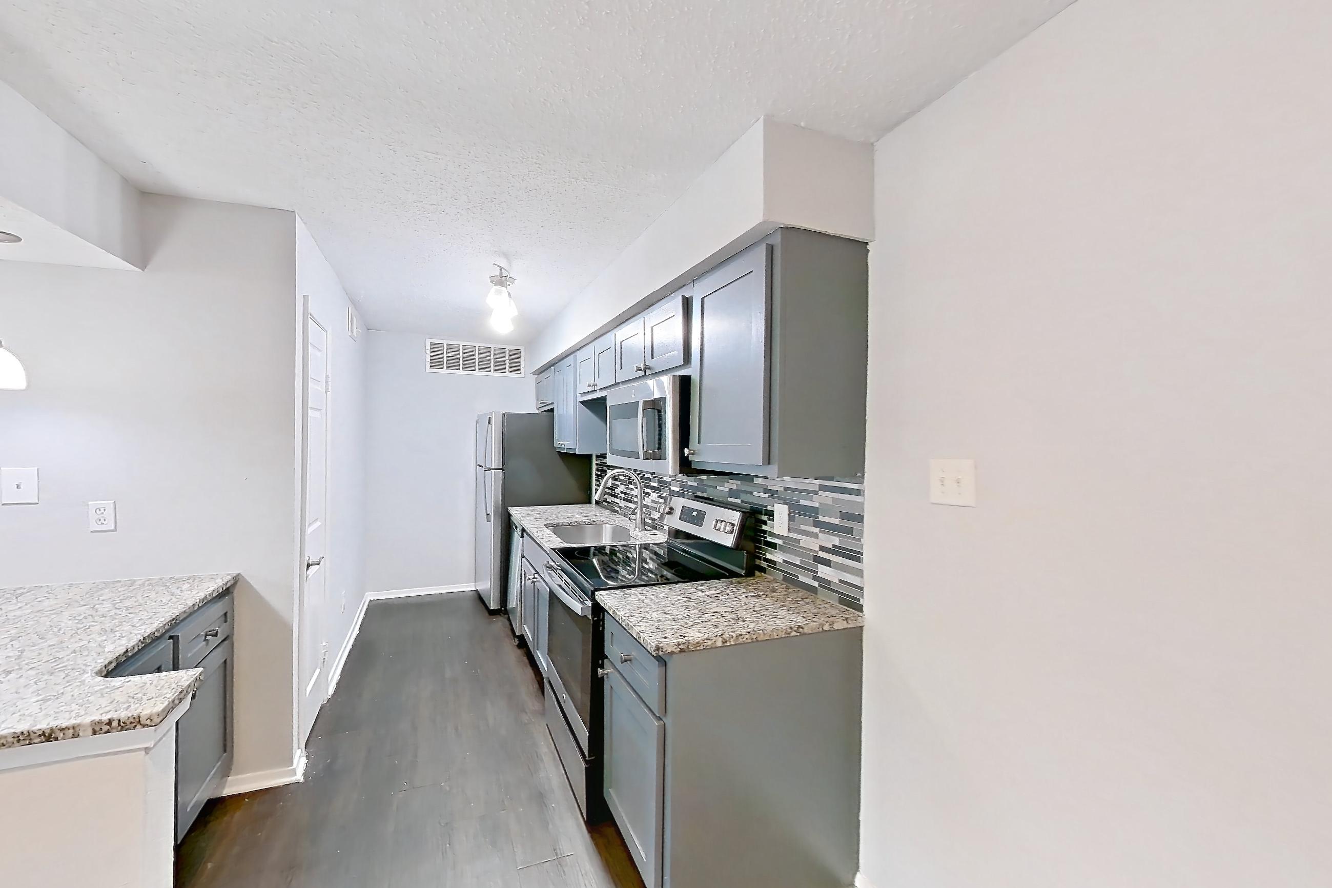 Dining room with dark wood-finish flooring, electric range, light countertops, light stone countertops, microwave, oven/range, and stainless steel appliances, Apartment 803 at Marine Creek Apartments
