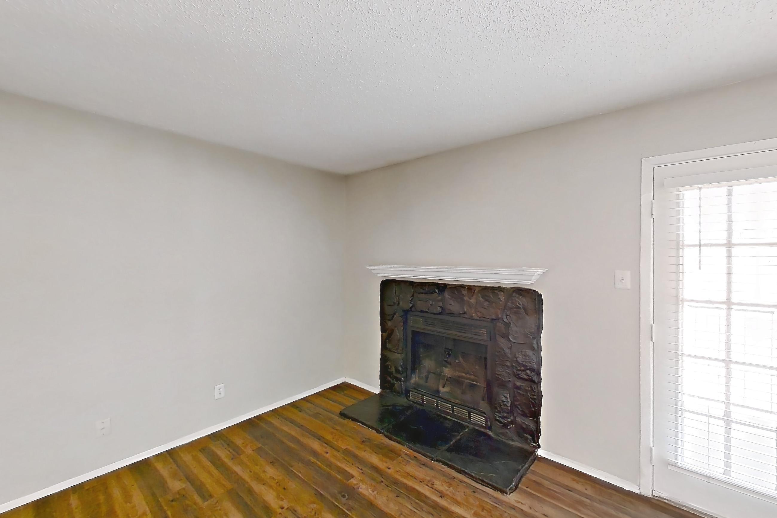 Living room with dark wood-finish flooring, fireplace, and stone fireplace, Apartment 902 at Marine Creek Apartments