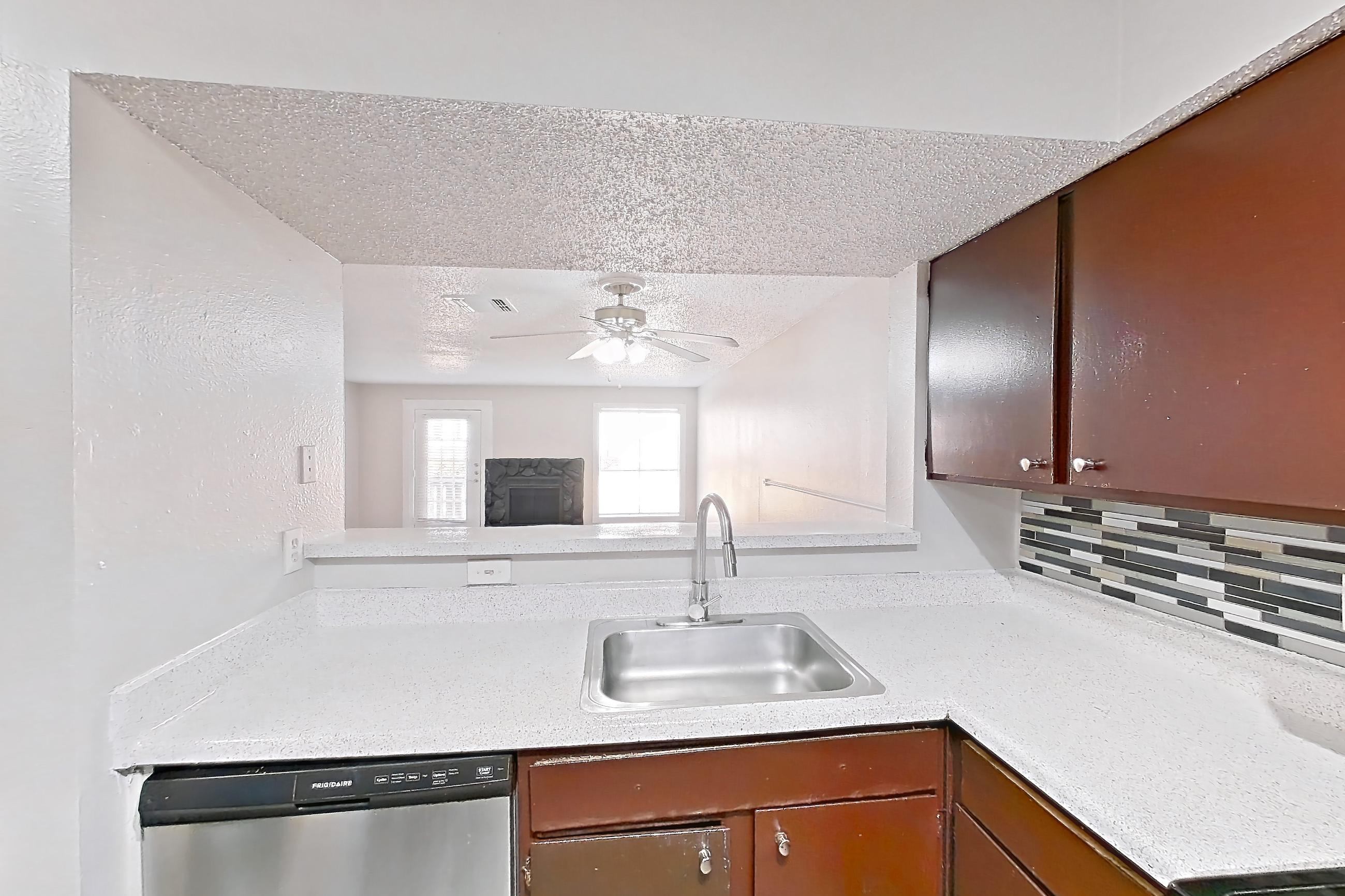 Kitchen with dishwasher, electric range, light countertops, light stone countertops, light wood-finish flooring, microwave, oven/range, refrigerator, and stainless steel appliances, Apartment 1113 at Marine Creek Apartments