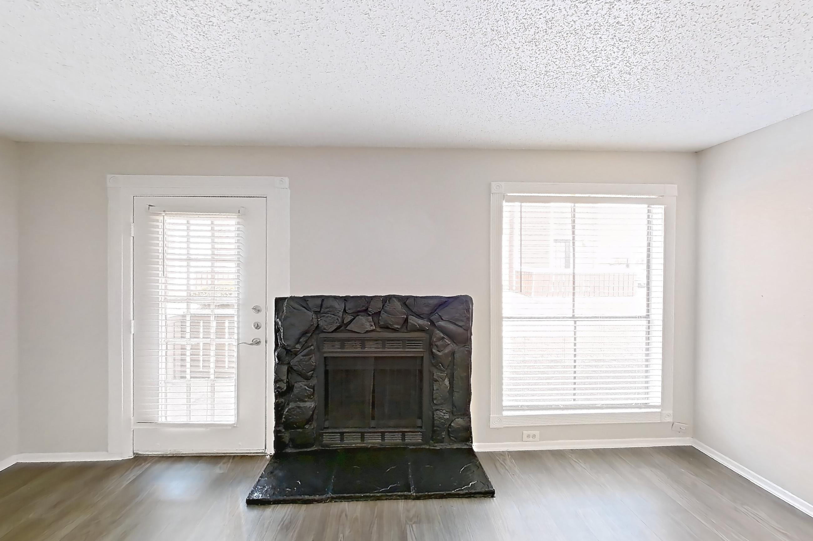 Living room with dark wood-finish flooring, fireplace, and stone fireplace, Apartment 1113 at Marine Creek Apartments