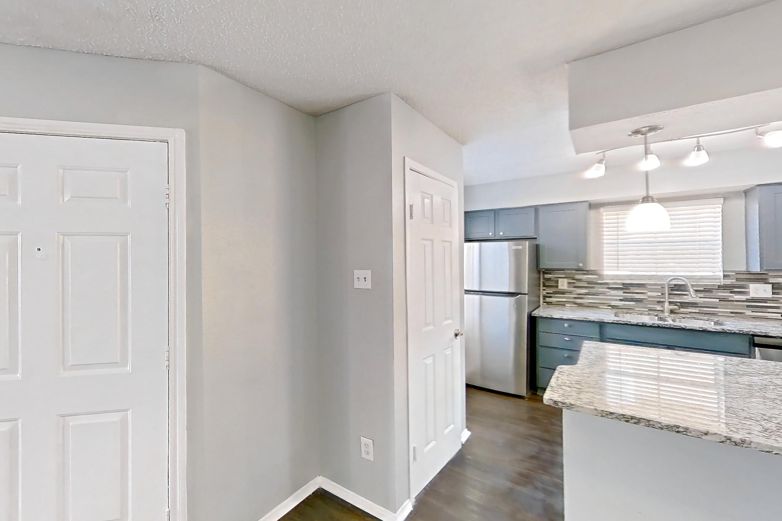 Dining room with dark wood-finish flooring, dishwasher, light countertops, light stone countertops, refrigerator, and stainless steel appliances, Apartment 1207 at Marine Creek Apartments