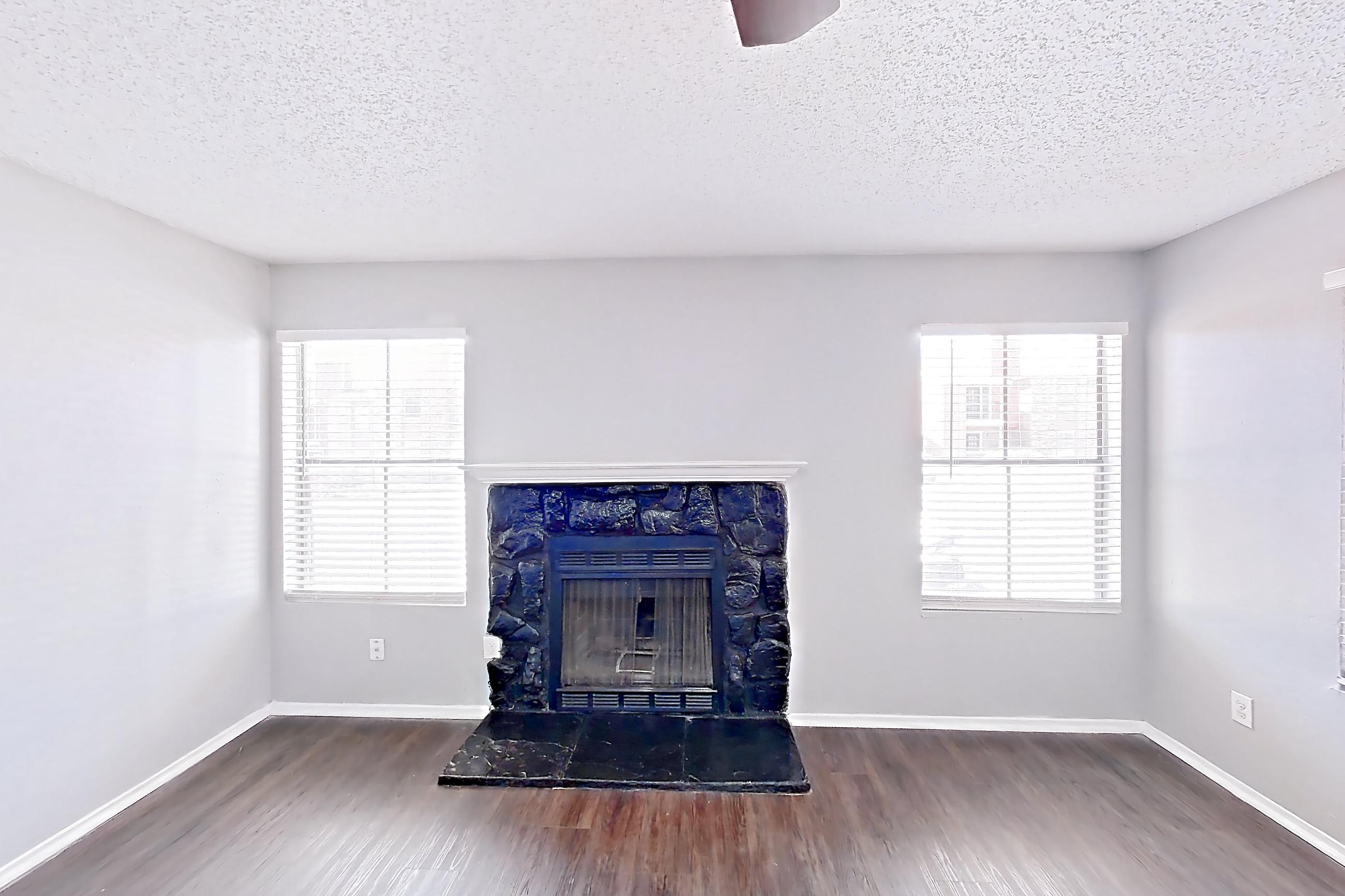 Living room with dark wood-finish flooring, fireplace, and stone fireplace, Apartment 1207 at Marine Creek Apartments