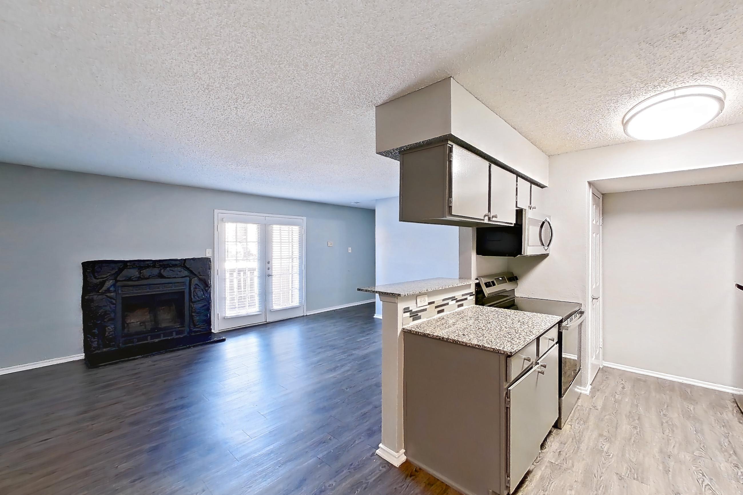 Dining room with dark wood-finish flooring, electric range, fireplace, light countertops, light stone countertops, oven/range, stainless steel appliances, and stone fireplace, Apartment 1505 at Marine Creek Apartments