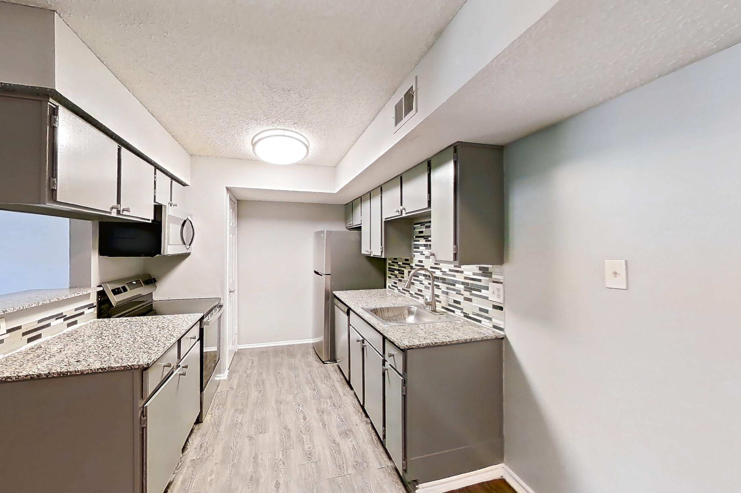 Dining room with dark wood-finish flooring, electric range, fireplace, light countertops, light stone countertops, oven/range, stainless steel appliances, and stone fireplace, Apartment 1505 at Marine Creek Apartments