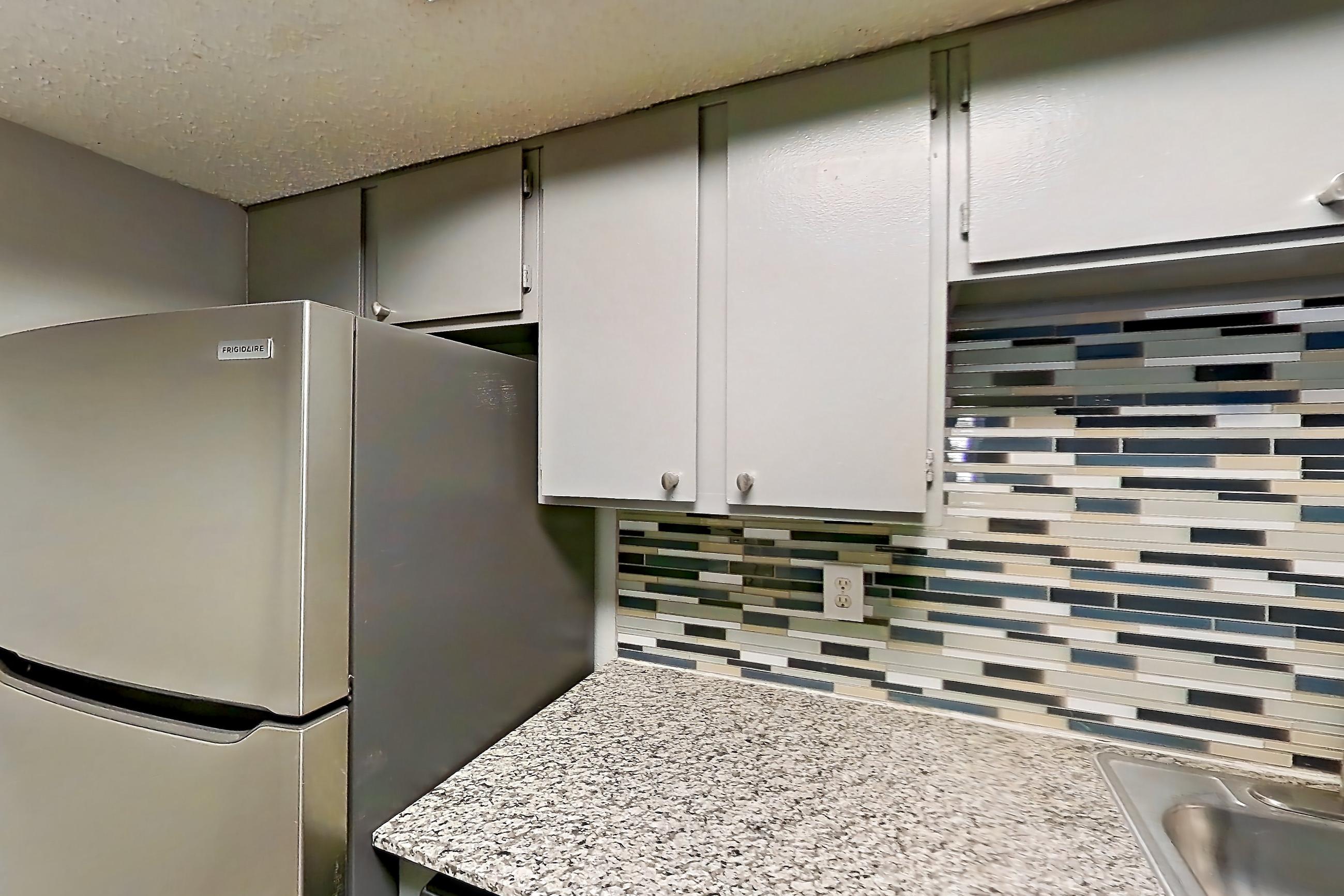 Kitchen with dark wood-finish flooring, dishwasher, electric range, light countertops, light stone countertops, microwave, oven/range, and stainless steel appliances, Apartment 1505 at Marine Creek Apartments