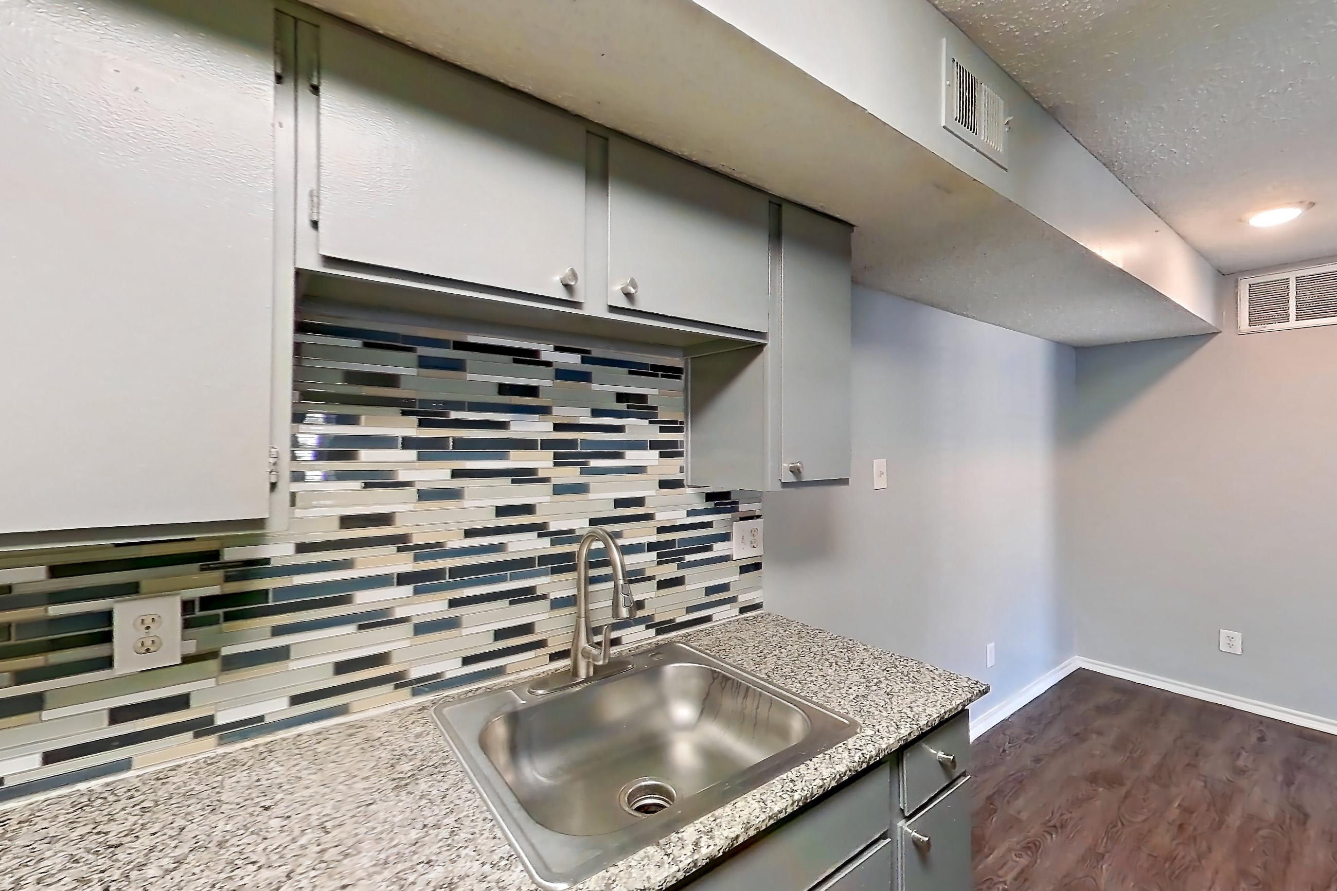 Kitchen with dark wood-finish flooring, dishwasher, electric range, light countertops, light stone countertops, microwave, oven/range, and stainless steel appliances, Apartment 1505 at Marine Creek Apartments