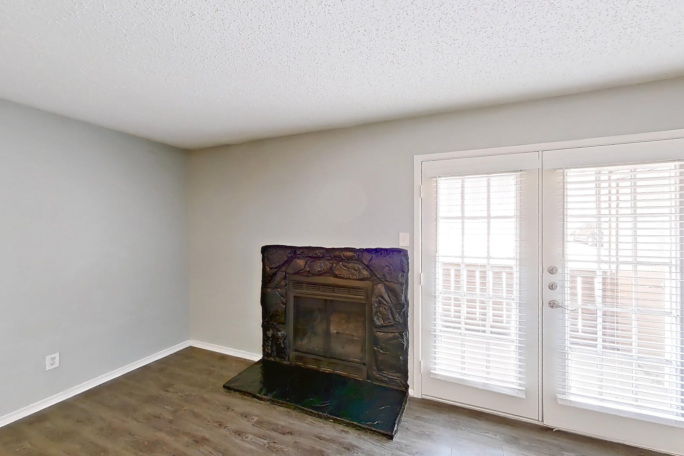 Living room with dark wood-finish flooring, fireplace, and stone fireplace, Apartment 1505 at Marine Creek Apartments
