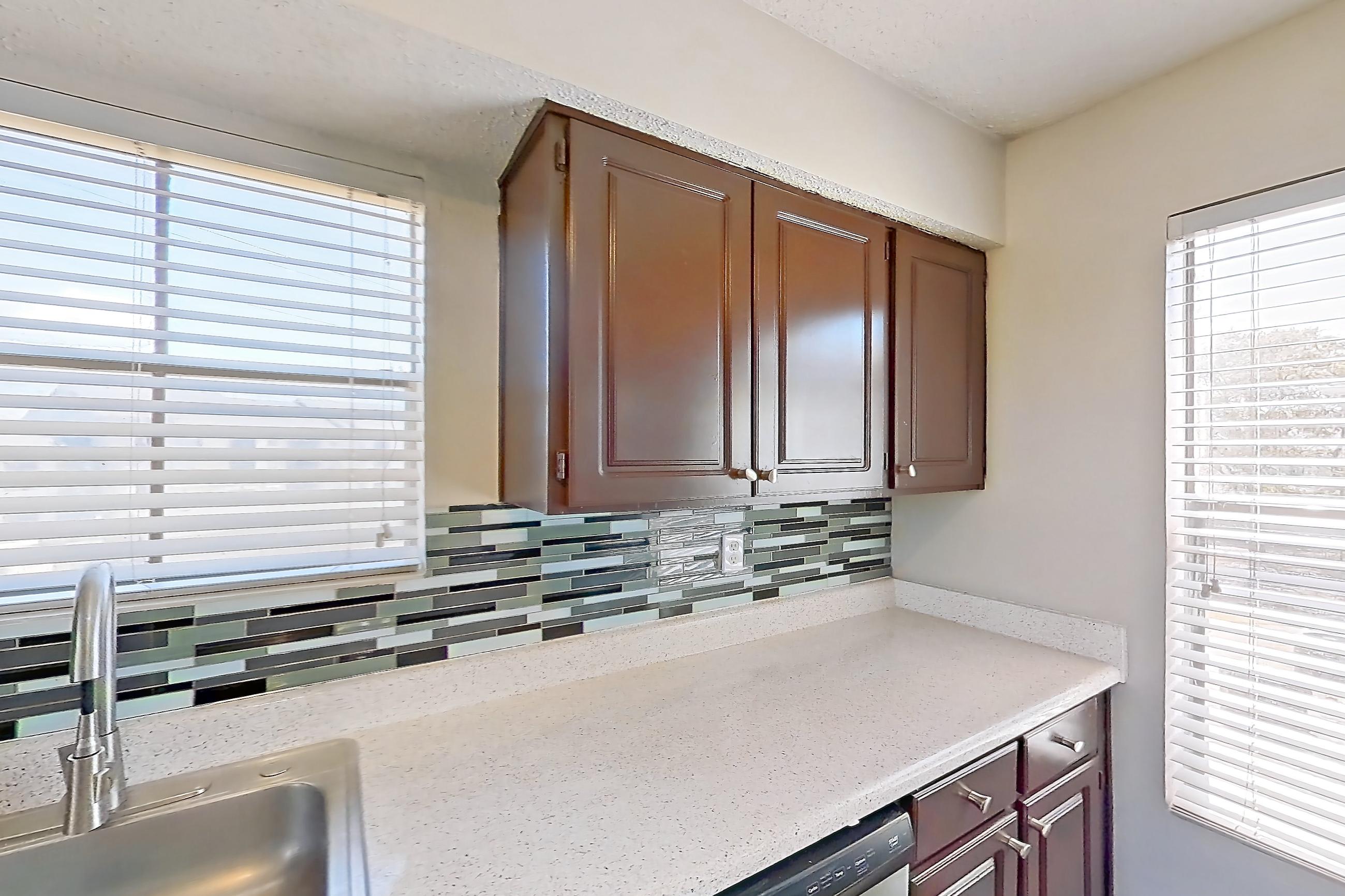 Kitchen with dishwasher, electric range, light countertops, light stone countertops, light wood-finish flooring, oven/range, refrigerator, and stainless steel appliances, Apartment 1606 at Marine Creek Apartments