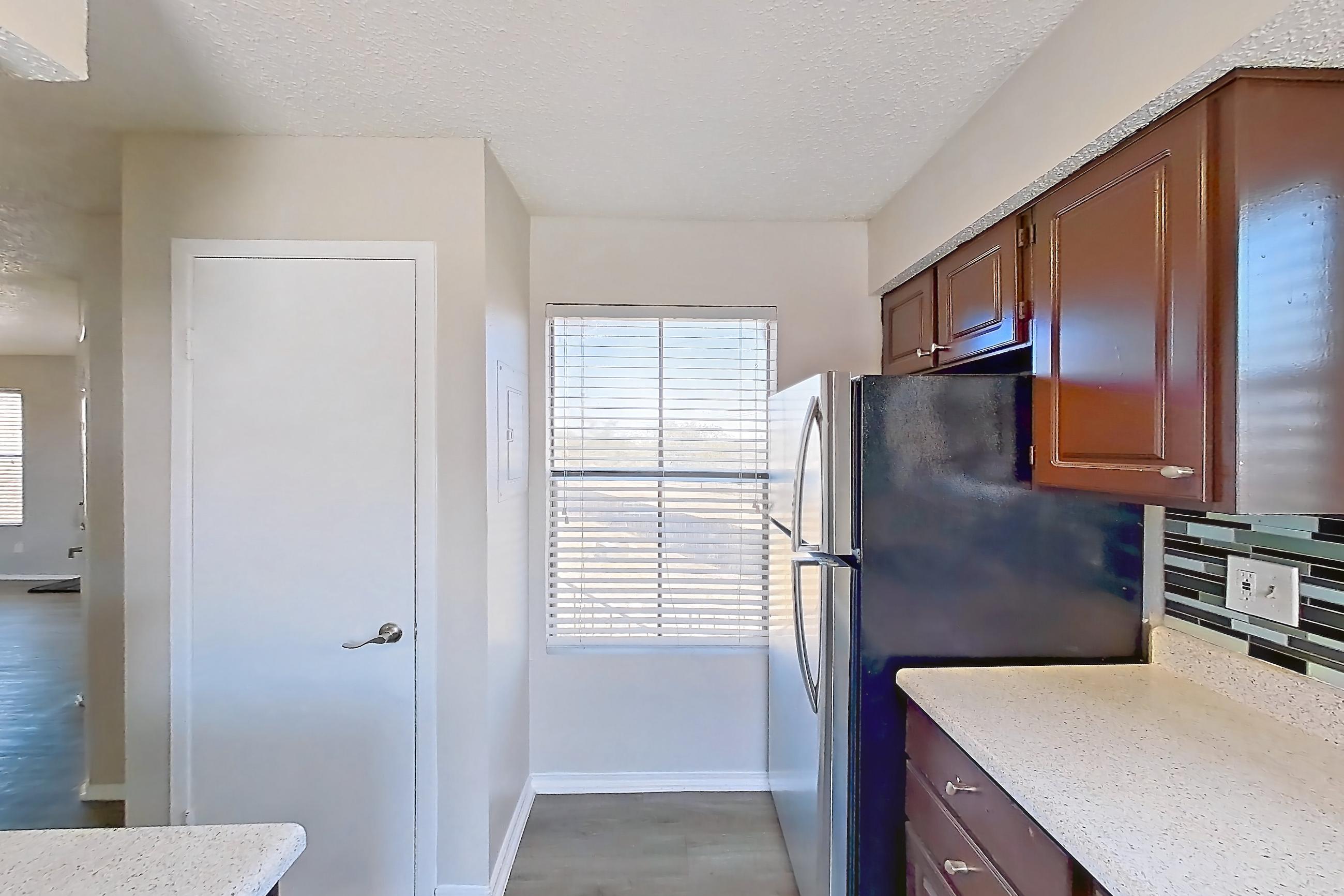 Kitchen with dishwasher, electric range, light countertops, light stone countertops, light wood-finish flooring, oven/range, refrigerator, and stainless steel appliances, Apartment 1606 at Marine Creek Apartments