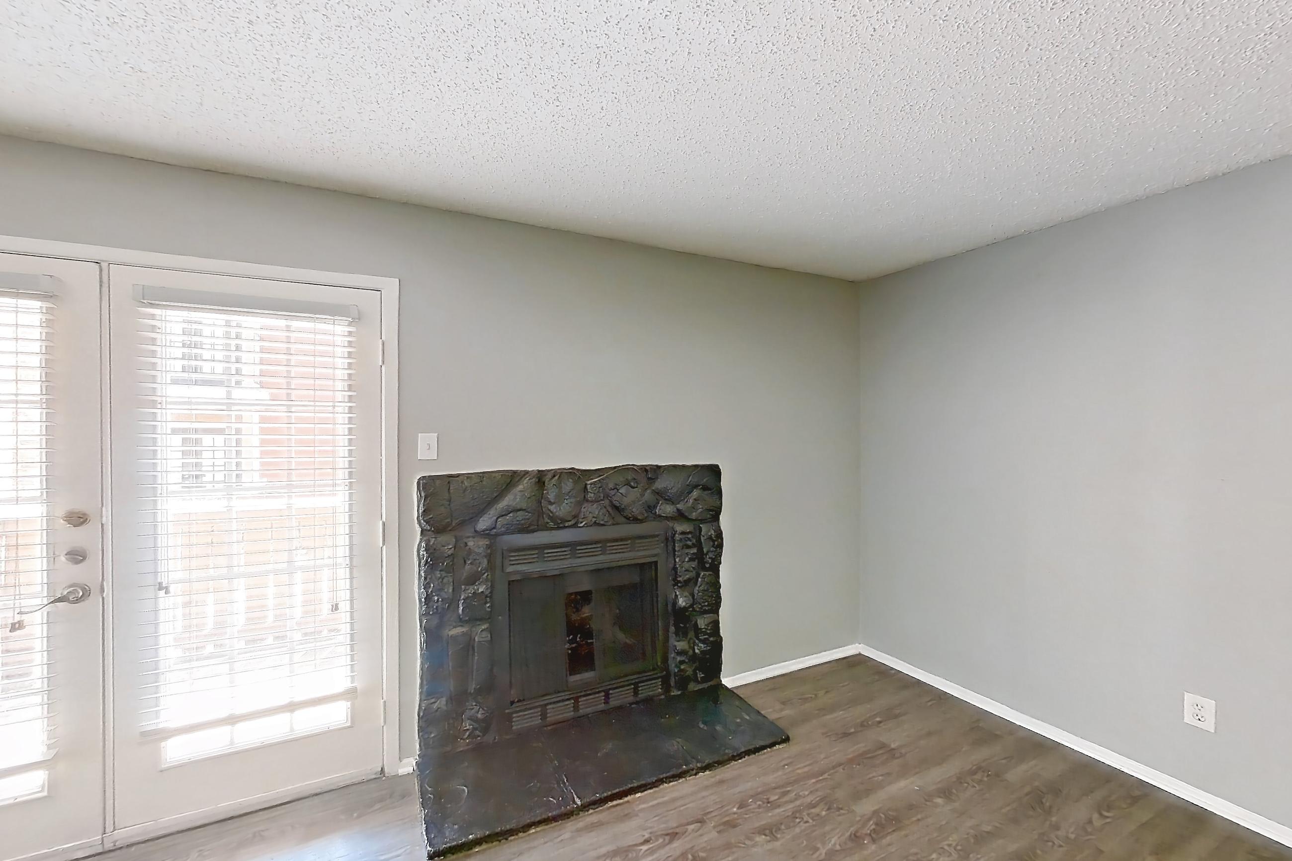 Living room with dark wood-finish flooring, fireplace, and stone fireplace, Apartment 1801 at Marine Creek Apartments