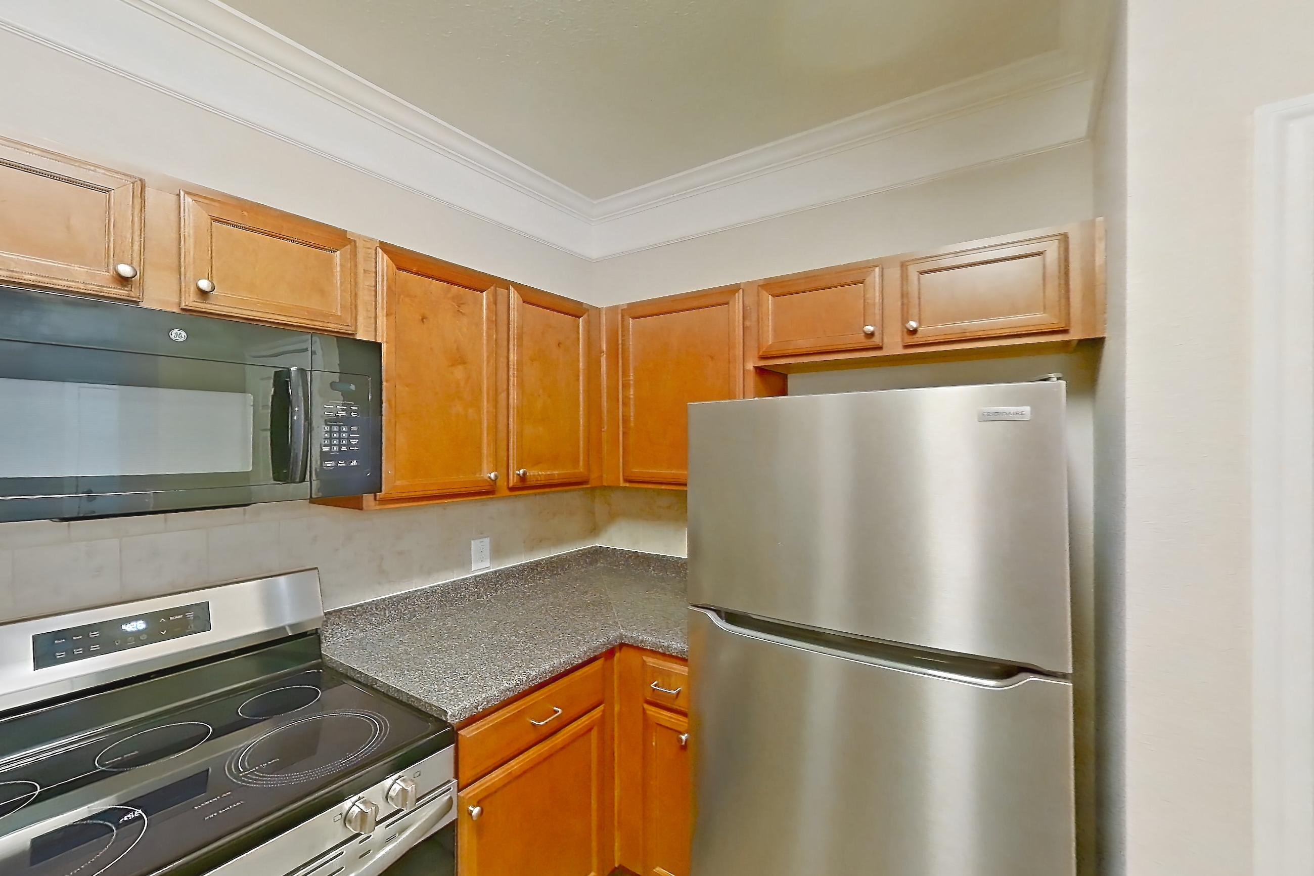Kitchen with black appliances, dark countertops, dark wood-finish flooring, dishwasher, electric range, oven/range, refrigerator, and stainless steel appliances, Apartment 3101 at Terraces at Fall Creek