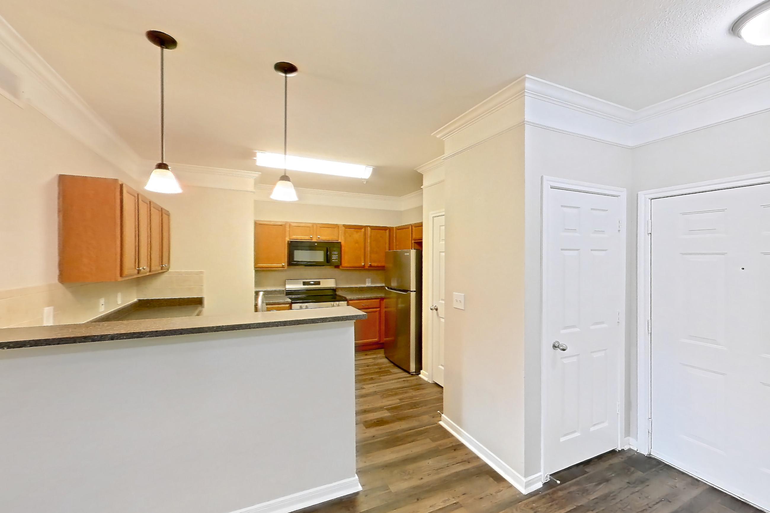 Living space with dark wood-finish flooring, electric range, oven/range, refrigerator, and stainless steel appliances, Apartment 3101 at Terraces at Fall Creek
