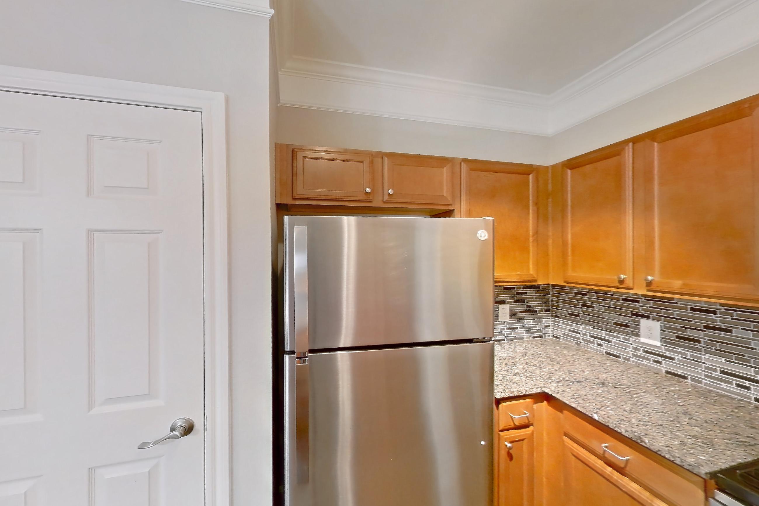 Kitchen with dark wood-finish flooring, dishwasher, electric range, light countertops, light stone countertops, oven/range, range hood, refrigerator, and stainless steel appliances, Apartment 3306 at Terraces at Fall Creek