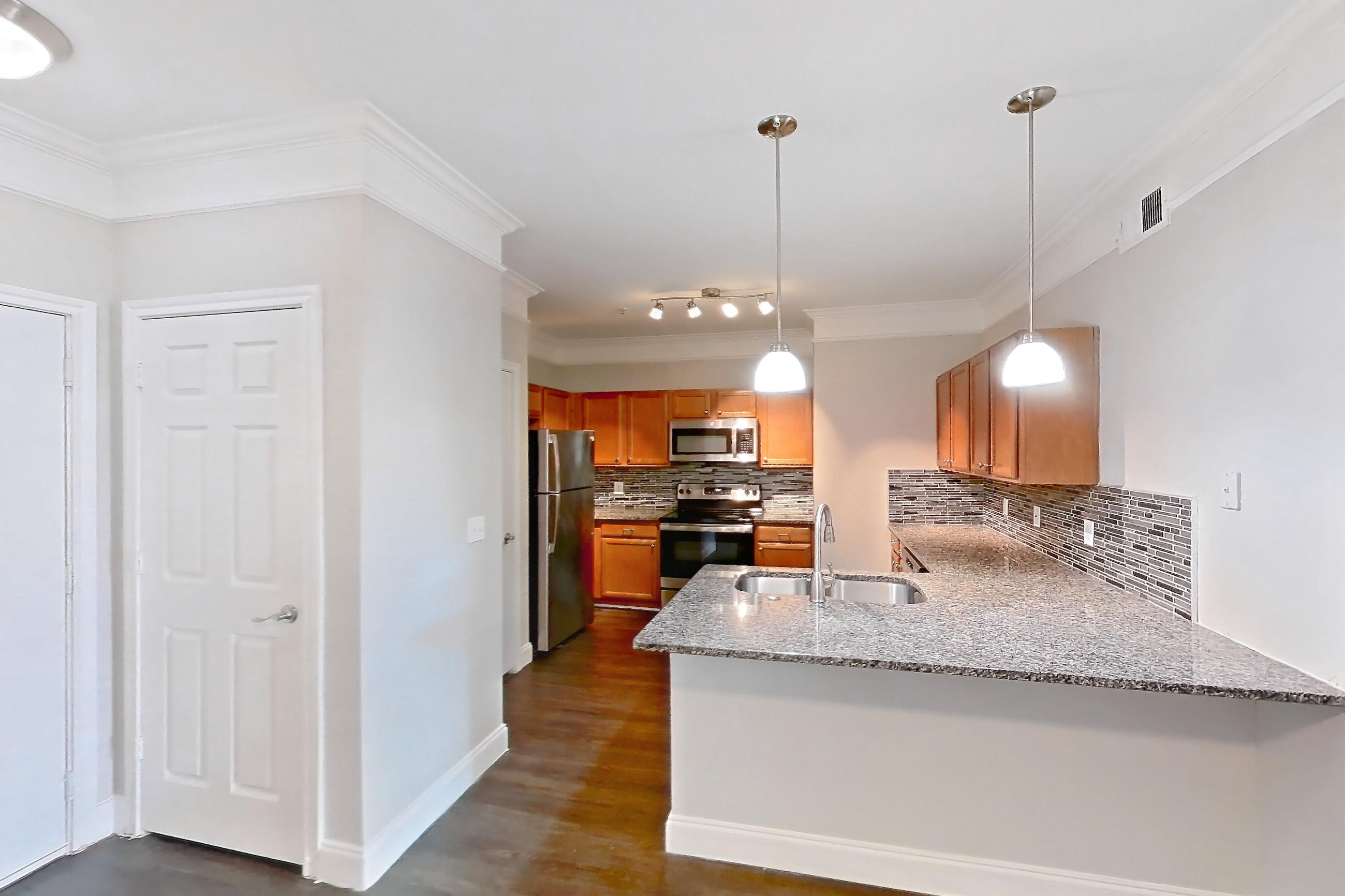Living space with dark wood-finish flooring, electric range, light stone countertops, oven/range, refrigerator, and stainless steel appliances, Apartment 3306 at Terraces at Fall Creek