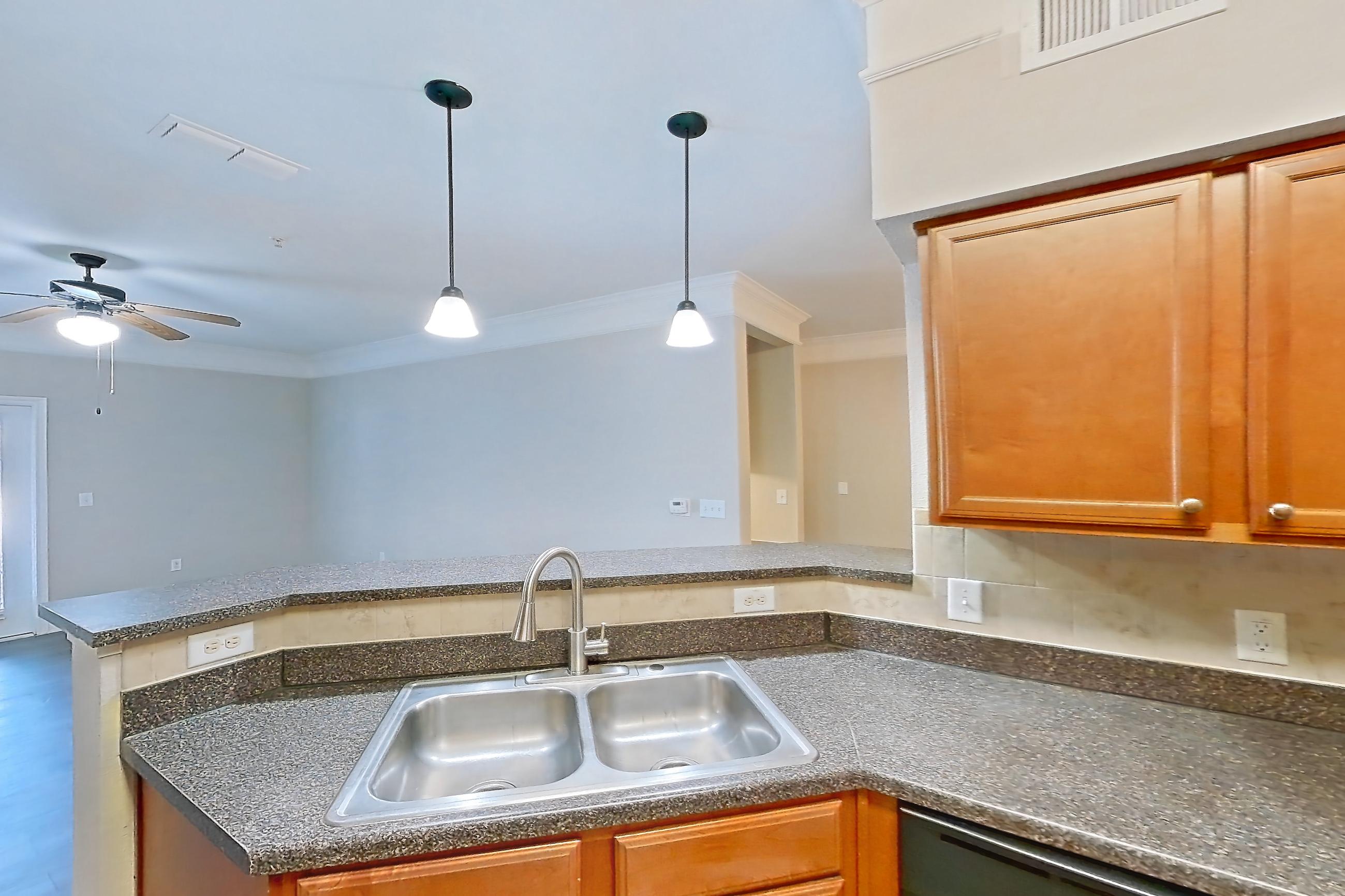 Kitchen with black appliances, dark countertops, dark stone countertops, dark wood-finish flooring, dishwasher, electric range, light wood-finish flooring, microwave, oven/range, refrigerator, and stainless steel appliances, Apartment 5103 at Terraces at Fall Creek