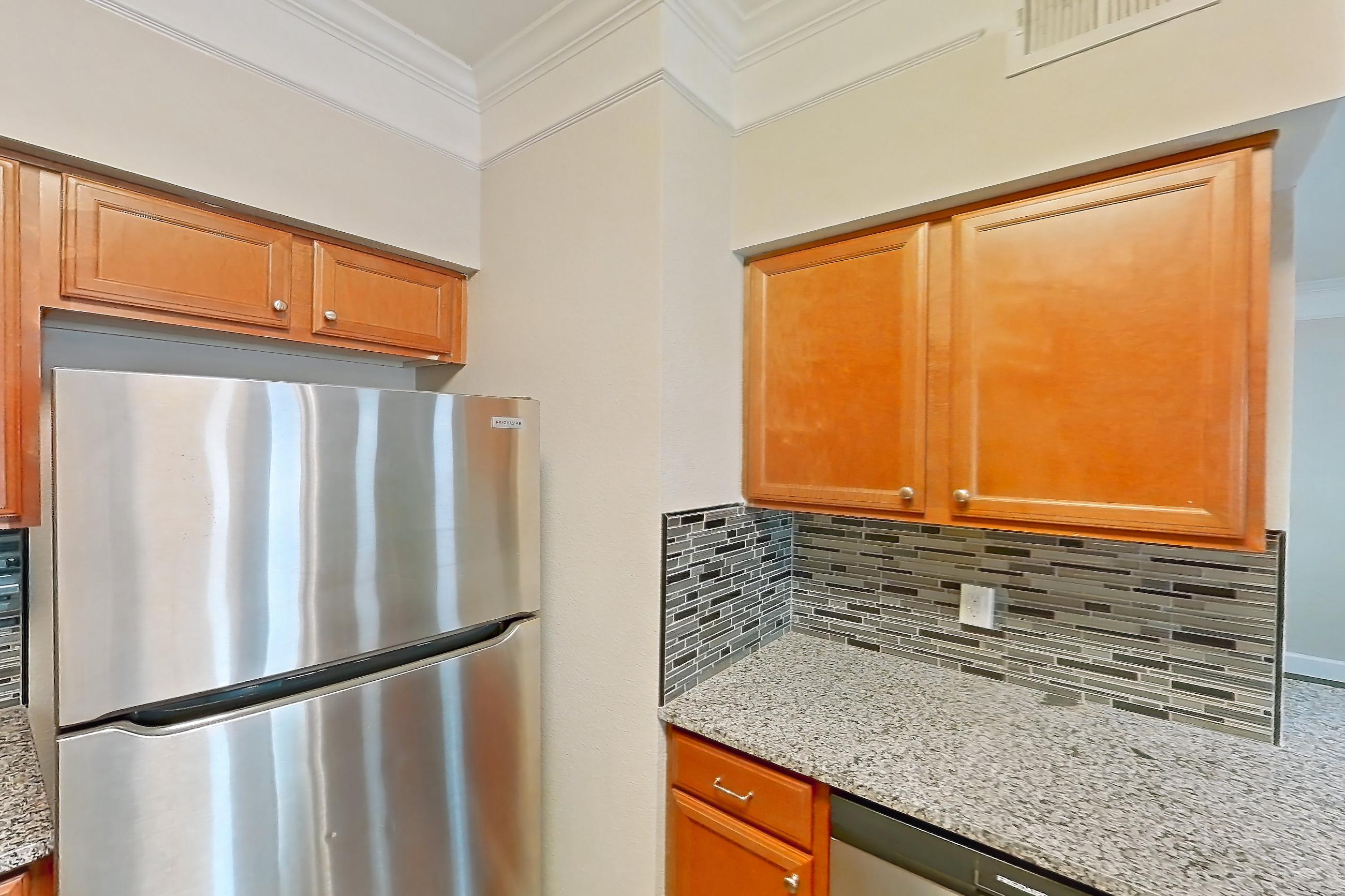 Kitchen with dark wood-finish flooring, dishwasher, electric range, light countertops, light stone countertops, microwave, oven/range, refrigerator, and stainless steel appliances, Apartment 5104 at Terraces at Fall Creek