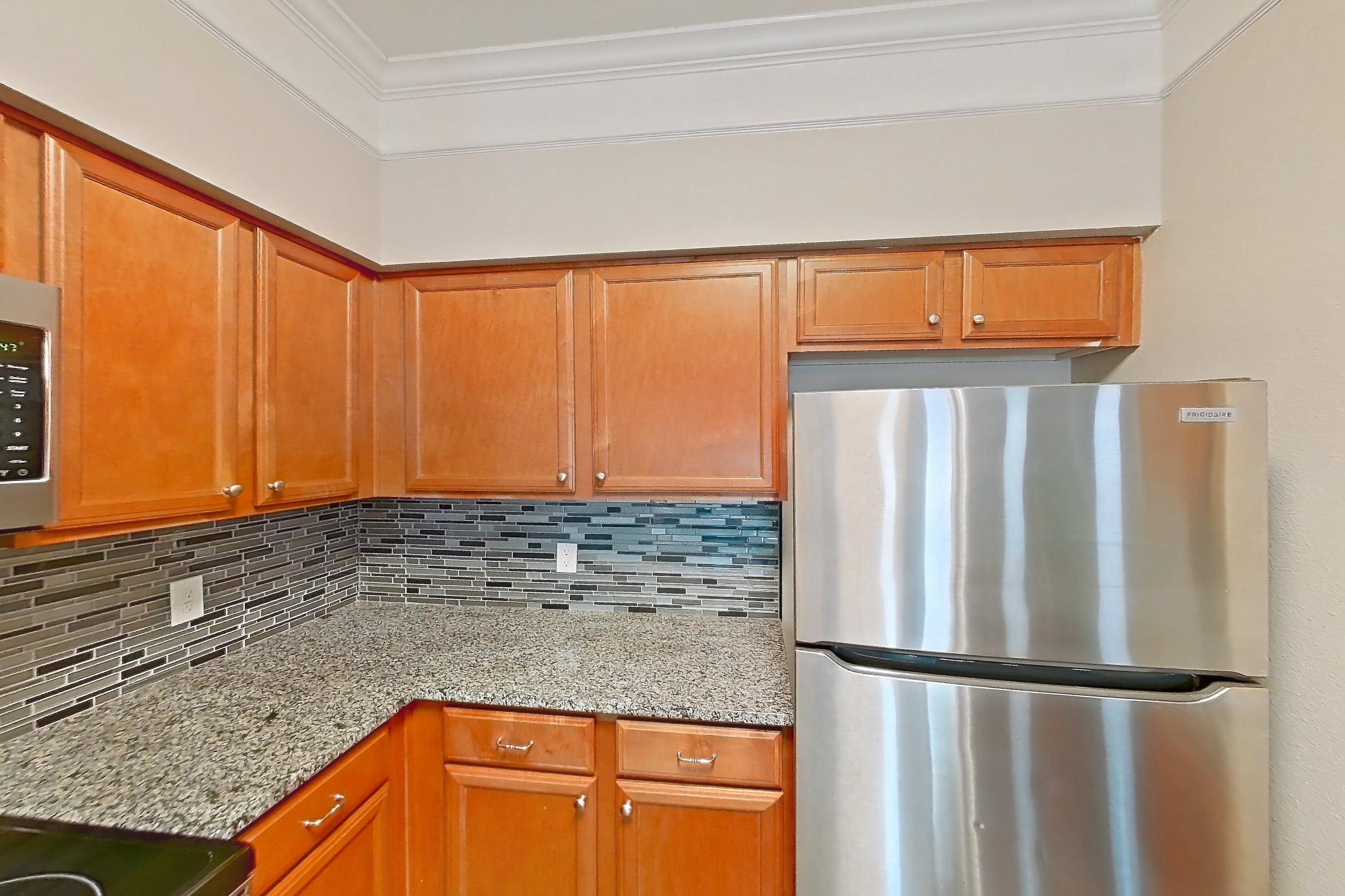 Kitchen with dark wood-finish flooring, dishwasher, electric range, light countertops, light stone countertops, microwave, oven/range, refrigerator, and stainless steel appliances, Apartment 5104 at Terraces at Fall Creek