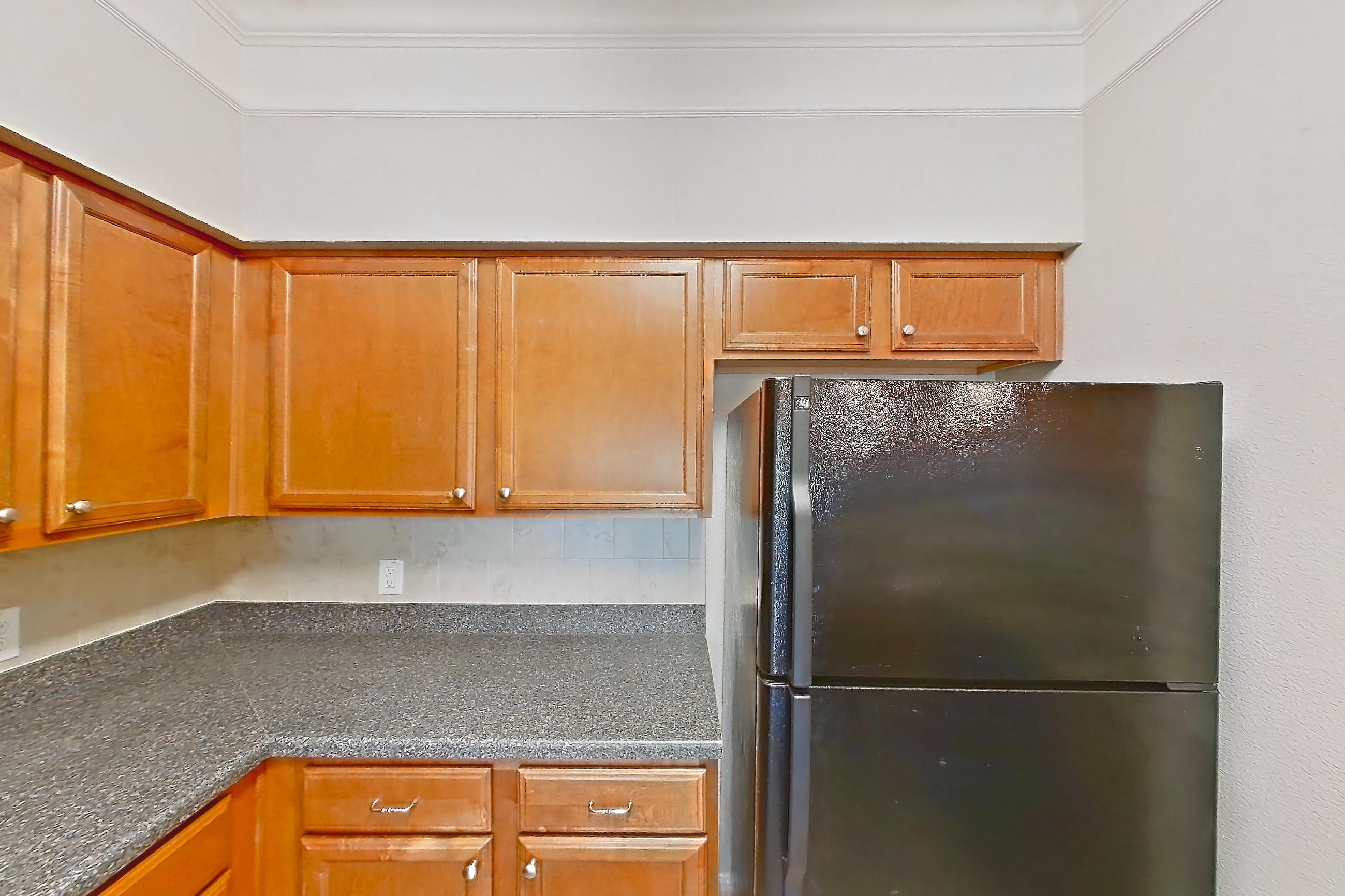 Kitchen with black appliances, dark countertops, dishwasher, electric range, light countertops, light wood-finish flooring, microwave, oven/range, and refrigerator, Apartment 7305 at Terraces at Fall Creek