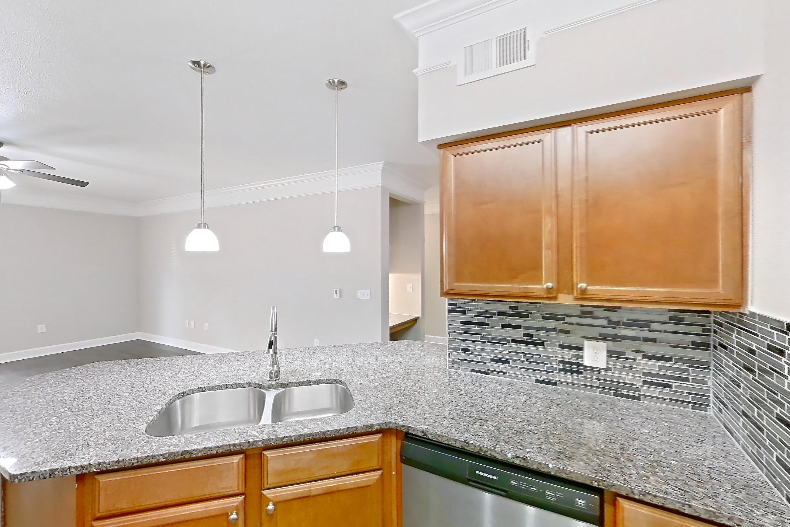Kitchen with dark stone countertops, dark wood-finish flooring, dishwasher, electric range, light stone countertops, microwave, oven/range, refrigerator, stainless steel appliances, and white appliances, Apartment 8102 at Terraces at Fall Creek