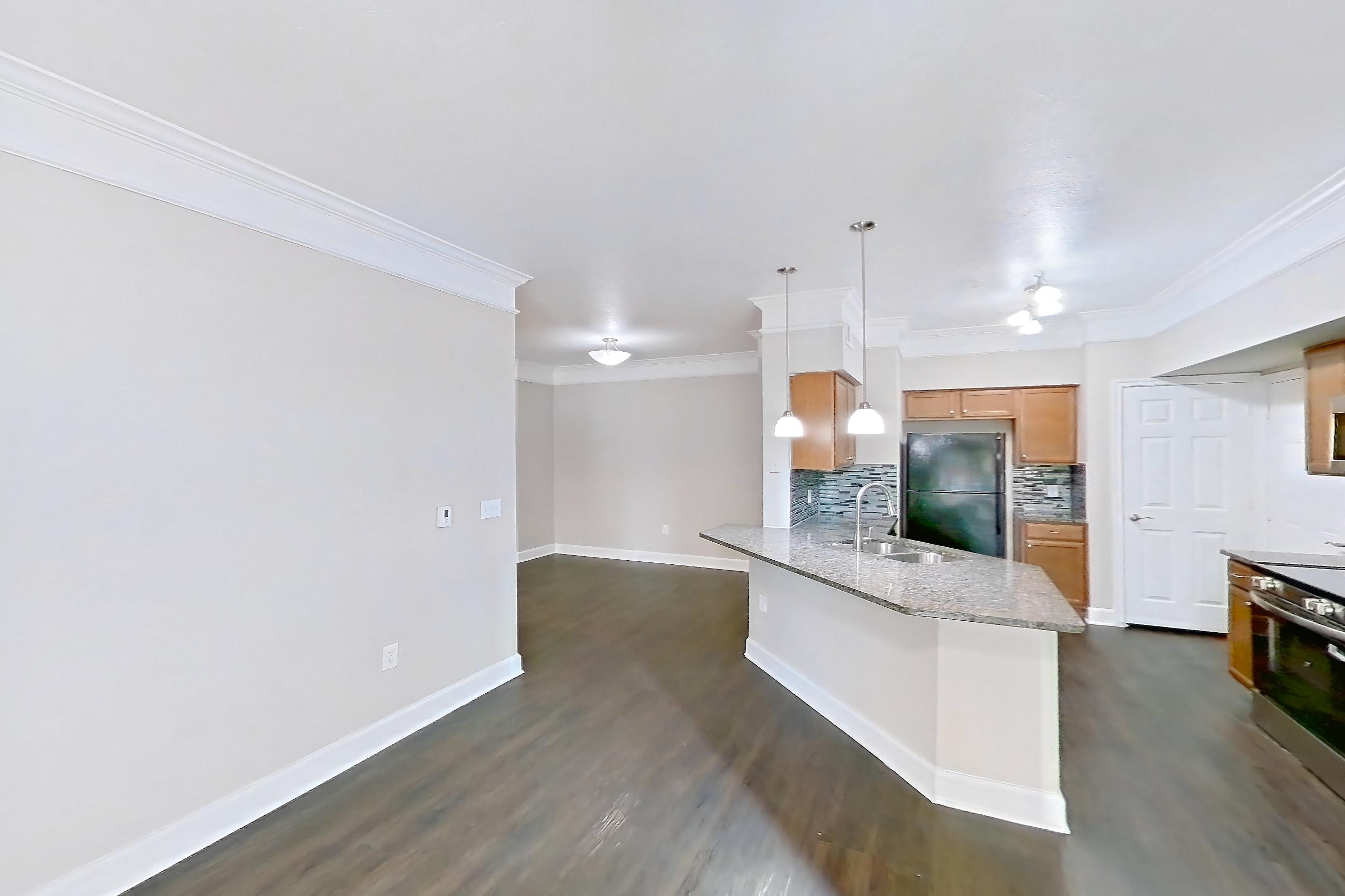 Living room with black appliances, dark wood-finish flooring, electric range, kitchen island, light stone countertops, oven/range, refrigerator, and stainless steel appliances, Apartment 8102 at Terraces at Fall Creek