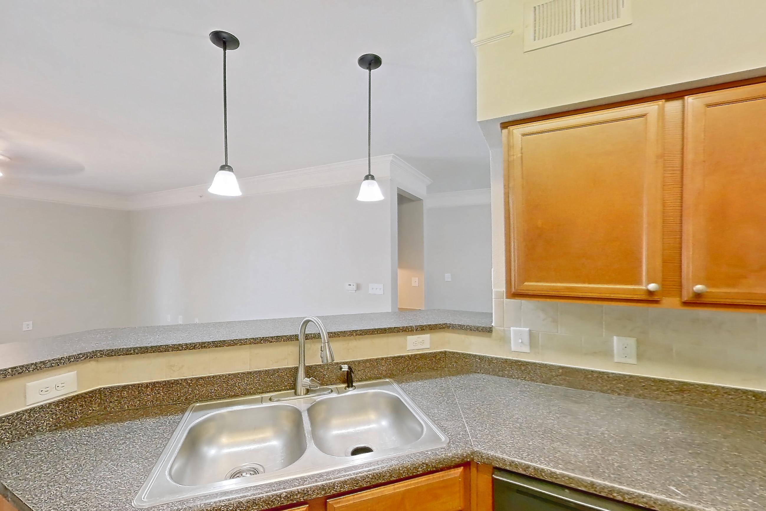 Kitchen with black appliances, dark countertops, dark stone countertops, dishwasher, electric range, light wood-finish flooring, microwave, oven/range, refrigerator, and stainless steel appliances, Apartment 8307 at Terraces at Fall Creek