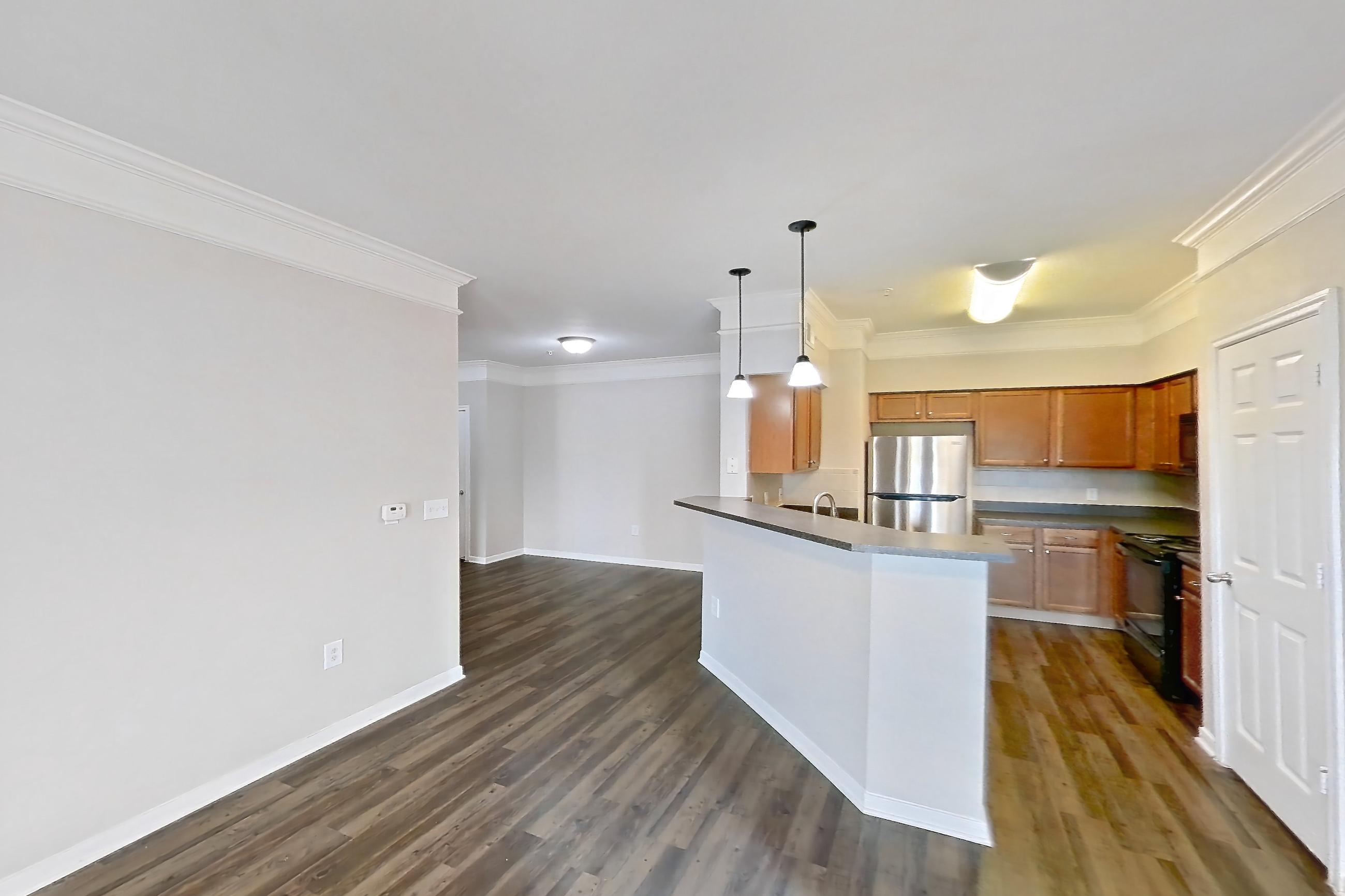 Living room with black appliances, dark countertops, dark wood-finish flooring, kitchen island, oven/range, refrigerator, and stainless steel appliances, Apartment 8307 at Terraces at Fall Creek