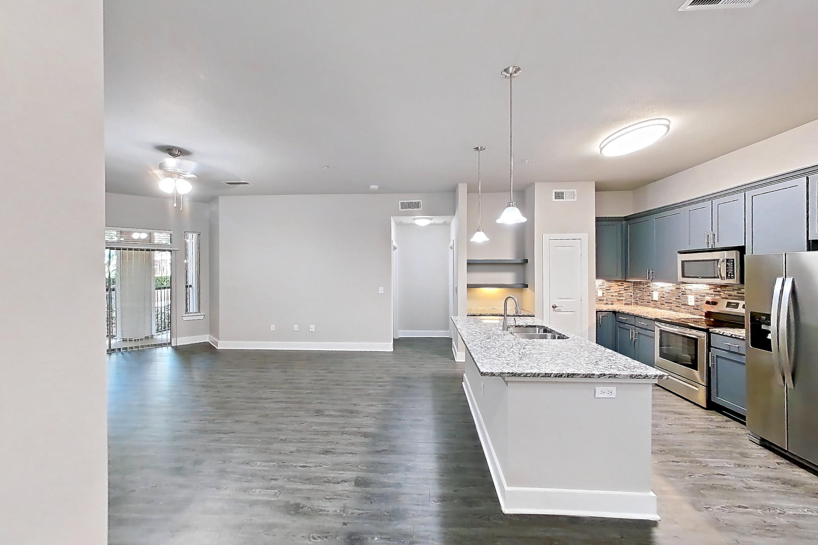 Dining room with dark wood-finish flooring, electric range, kitchen island, light stone countertops, oven/range, refrigerator, and stainless steel appliances, Apartment 144 at Voyager at the Space Center