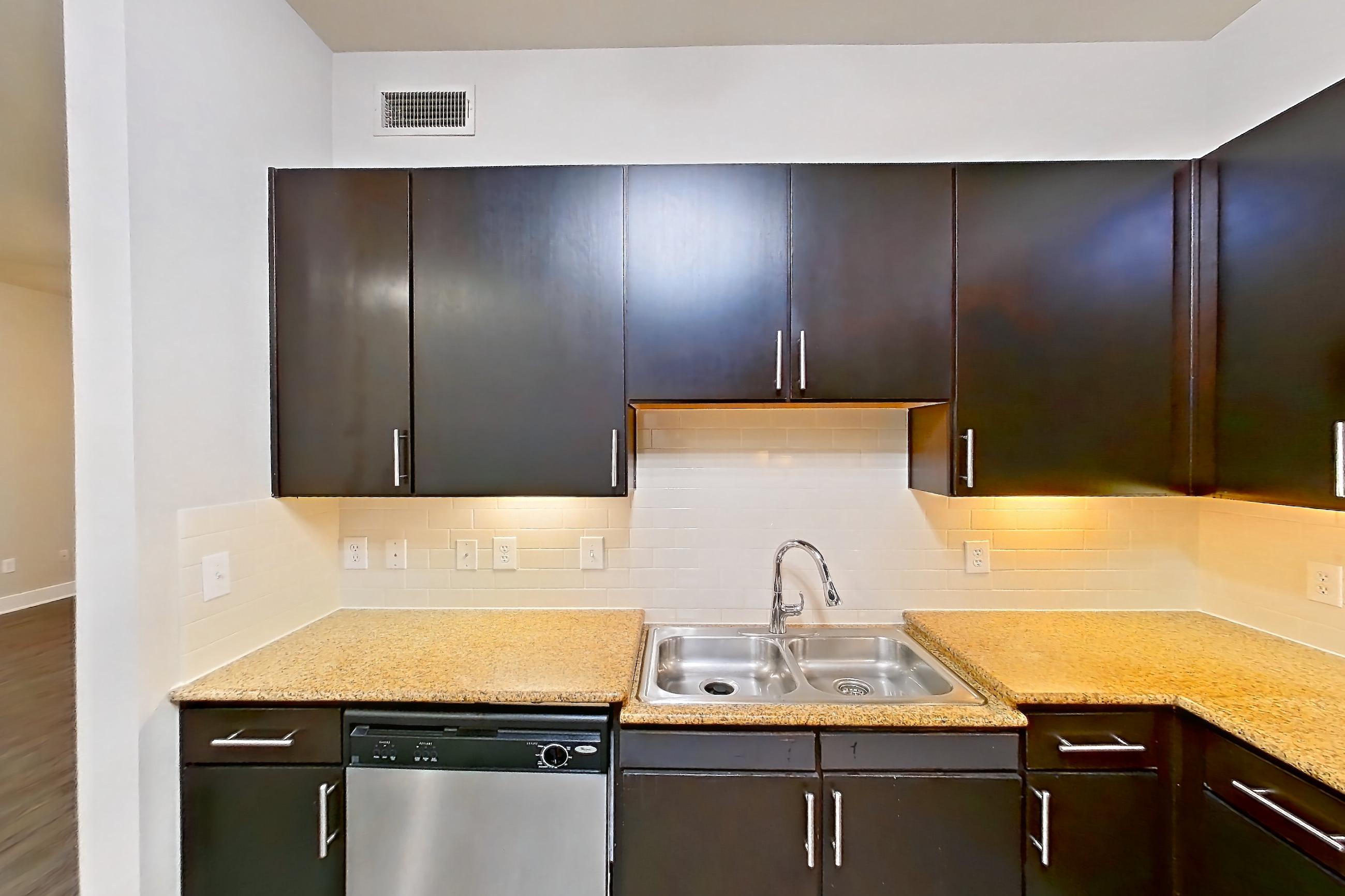 Kitchen with dishwasher, electric range, light stone countertops, light wood-finish flooring, microwave, oven/range, range hood, and stainless steel appliances, Apartment 176 at Voyager at the Space Center