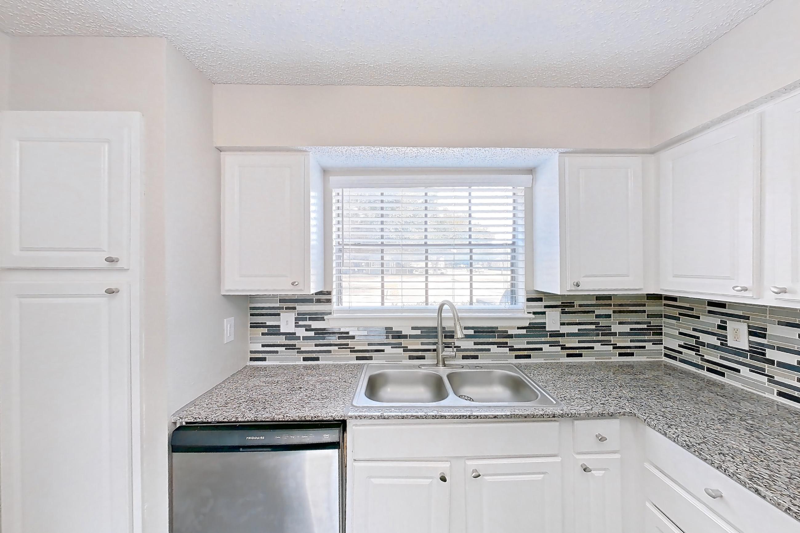Kitchen with dark wood-finish flooring, dishwasher, electric range, light countertops, light stone countertops, microwave, oven/range, refrigerator, and stainless steel appliances, Apartment 1011 at Creekside Village