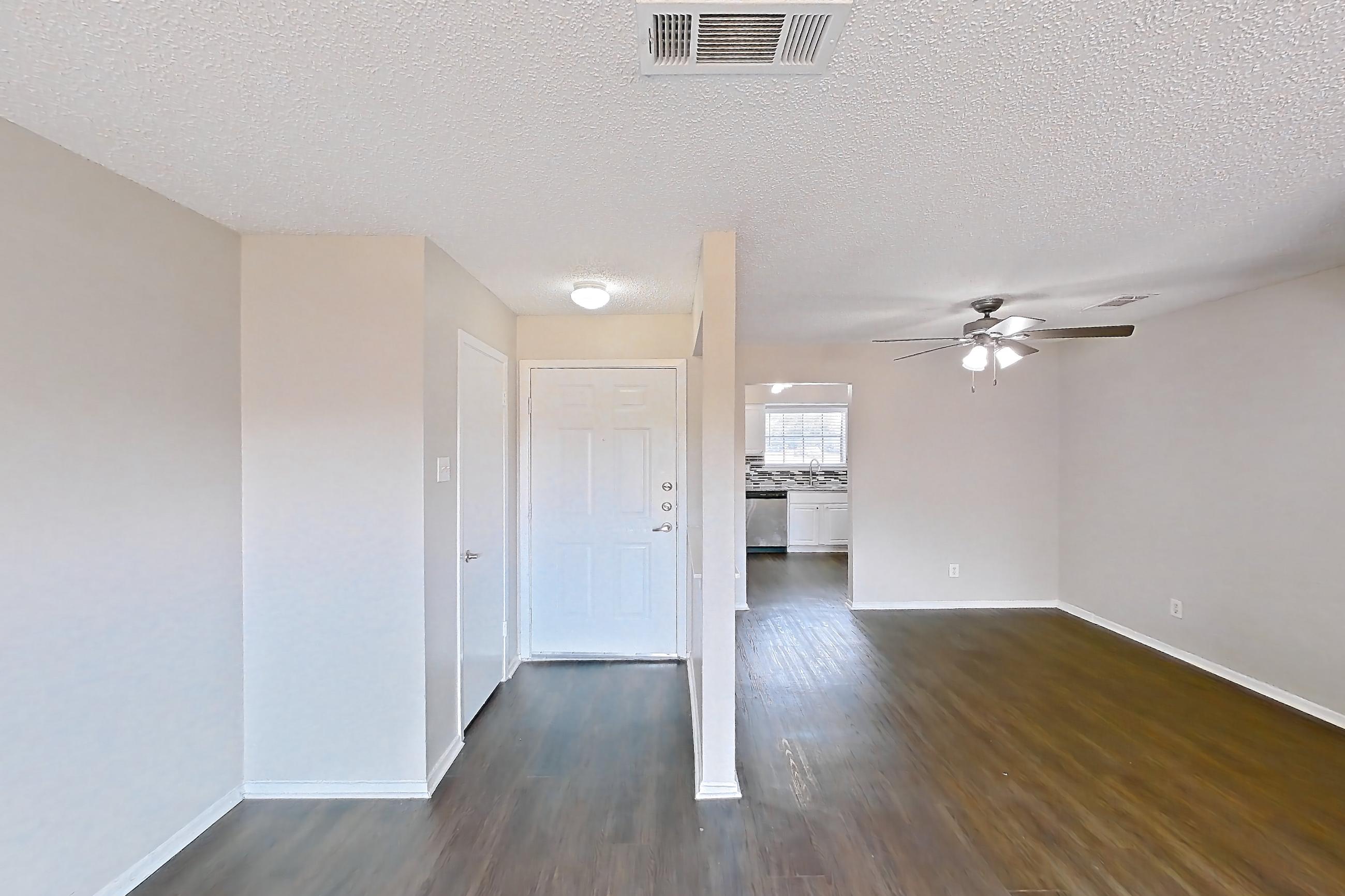 Living room with dark wood-finish flooring, dishwasher, fireplace, and stainless steel appliances, Apartment 1011 at Creekside Village