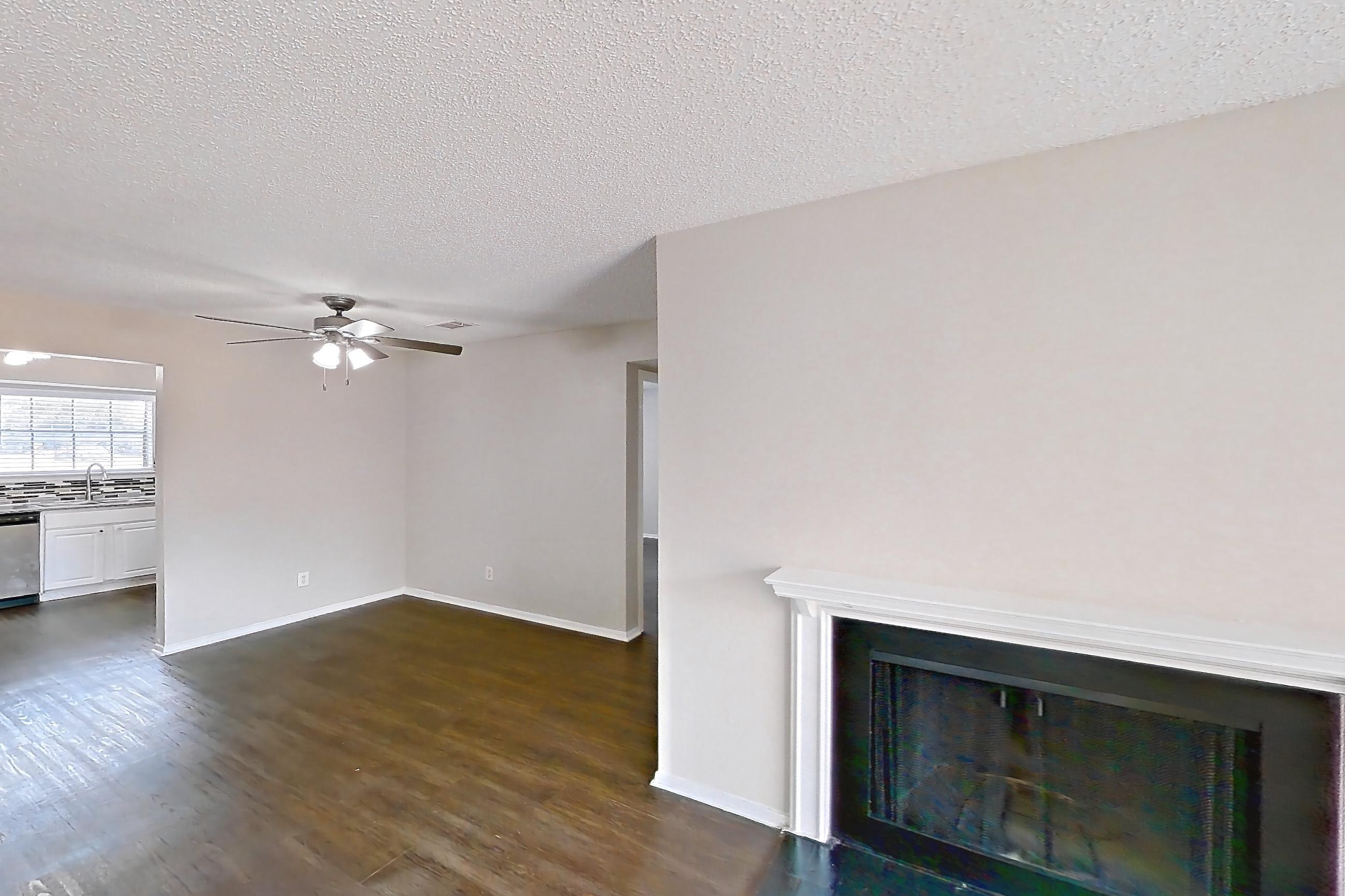 Living room with dark wood-finish flooring, dishwasher, fireplace, and stainless steel appliances, Apartment 1011 at Creekside Village