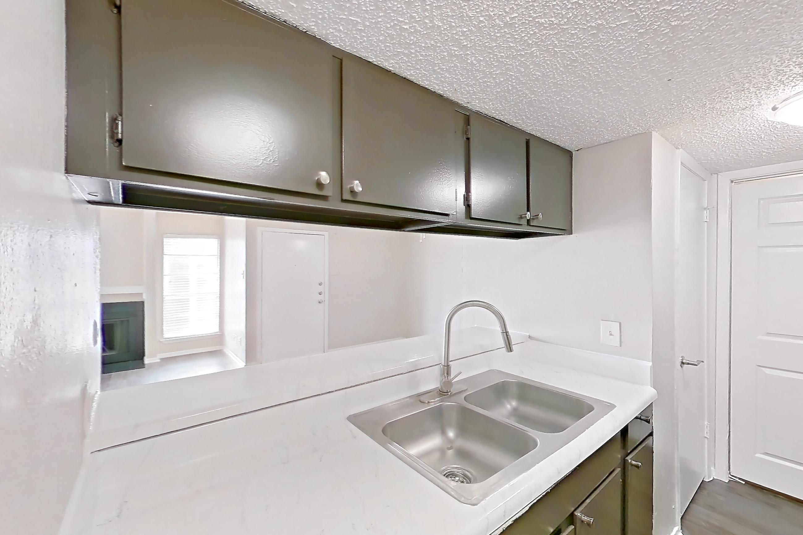 Kitchen with black appliances, dark wood-finish flooring, dishwasher, electric range, light countertops, light stone countertops, light wood-finish flooring, microwave, oven/range, refrigerator, and stainless steel appliances, Apartment 2825SC at The Cassidy at Western Hills