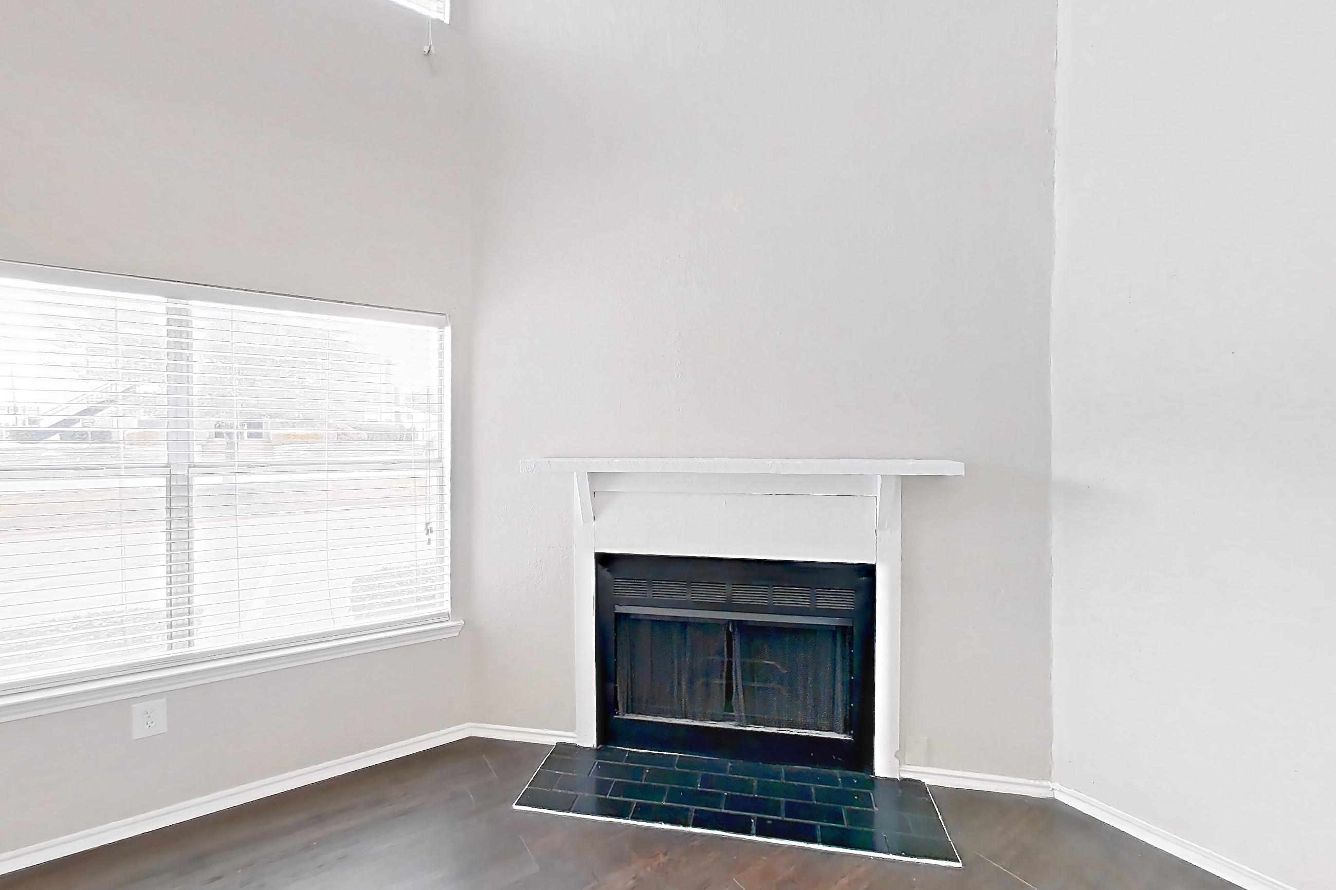 Living room with dark wood-finish flooring and fireplace, Apartment 103 at Quail Ridge Apartments