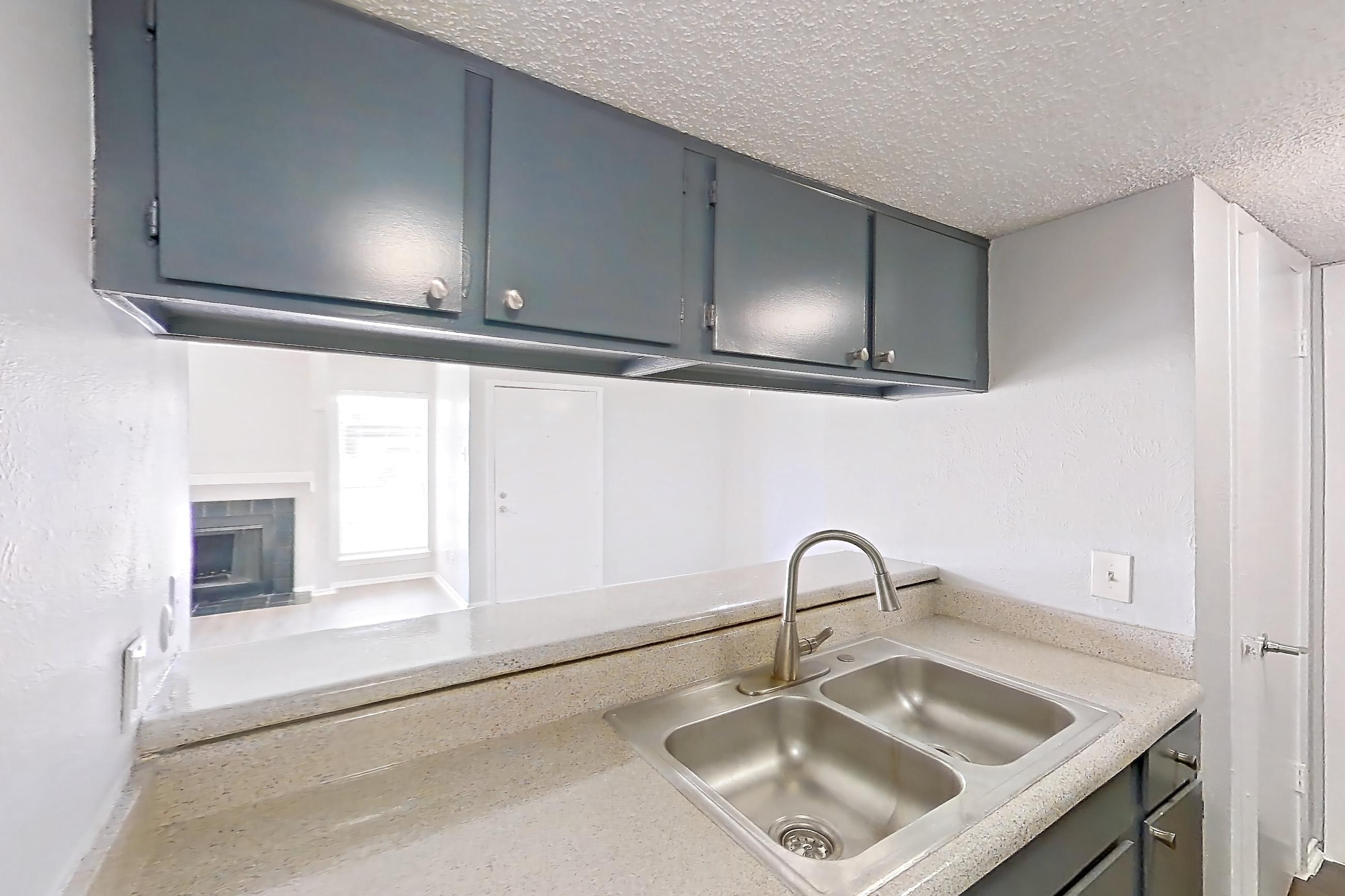Kitchen with dishwasher, electric range, fireplace, light countertops, light wood-finish flooring, microwave, oven/range, refrigerator, and stainless steel appliances, Apartment 8930SD at The Cassidy at Western Hills