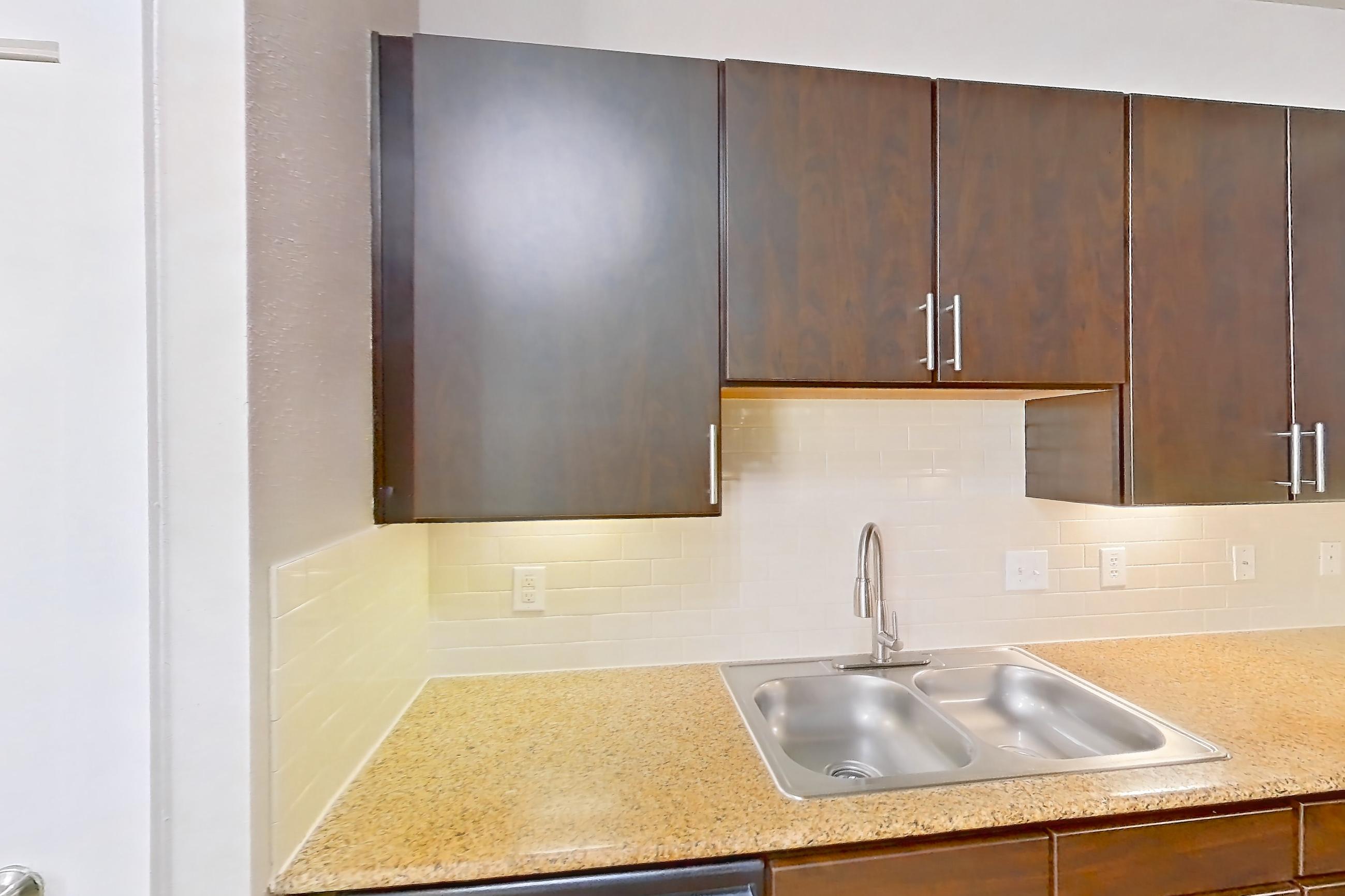 Kitchen with dishwasher, electric range, light stone countertops, light wood-finish flooring, oven/range, refrigerator, and stainless steel appliances, Apartment 371 at Voyager at the Space Center