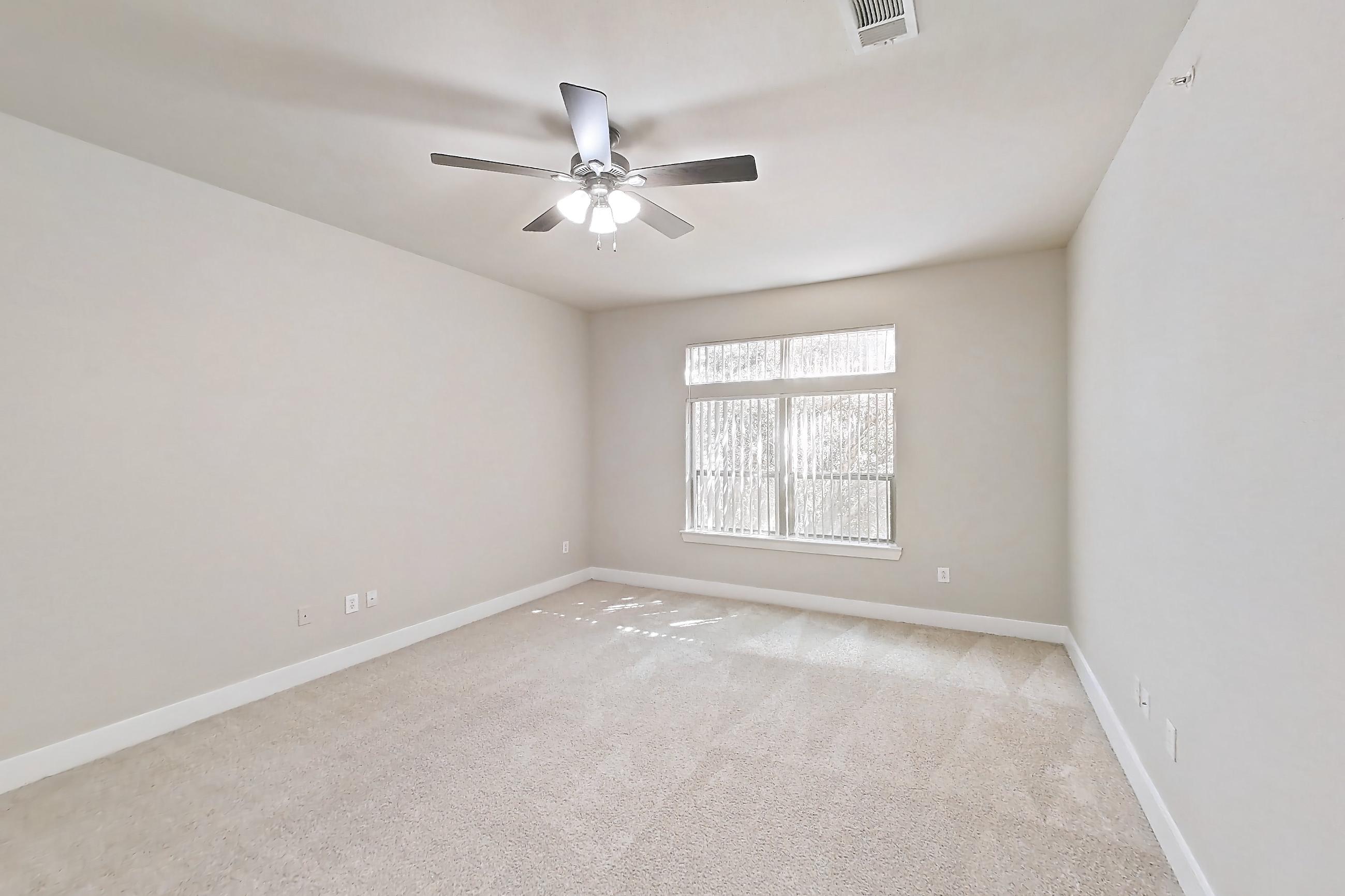 Living space with electric range, kitchen island, light carpet, light countertops, light stone countertops, oven/range, refrigerator, and stainless steel appliances, Apartment 373 at Voyager at the Space Center