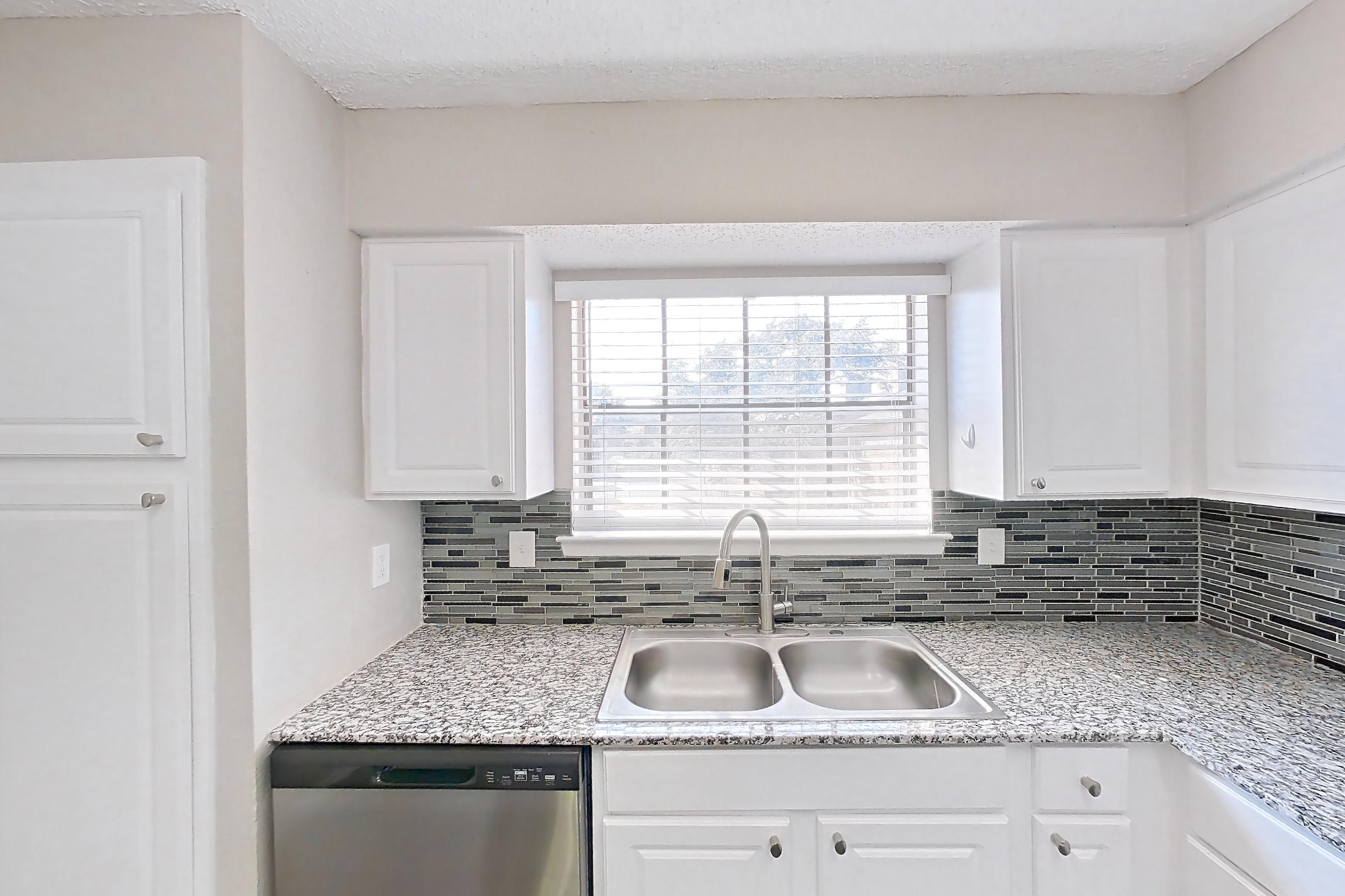 Kitchen with dark wood-finish flooring, dishwasher, electric range, light countertops, light stone countertops, microwave, oven/range, refrigerator, and stainless steel appliances, Apartment 2181 at Creekside Village