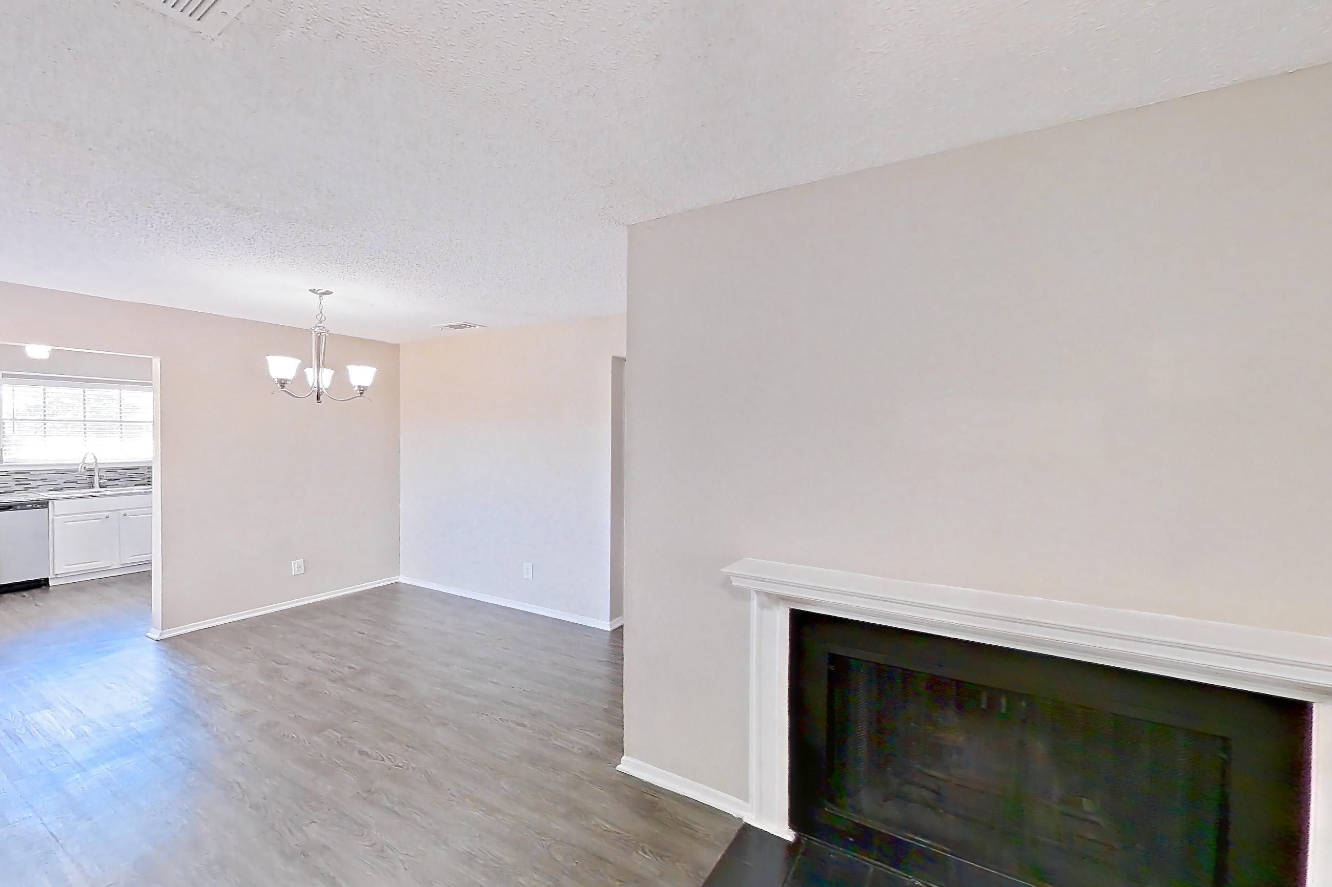 Living room with dark wood-finish flooring, dishwasher, fireplace, and stainless steel appliances, Apartment 2181 at Creekside Village