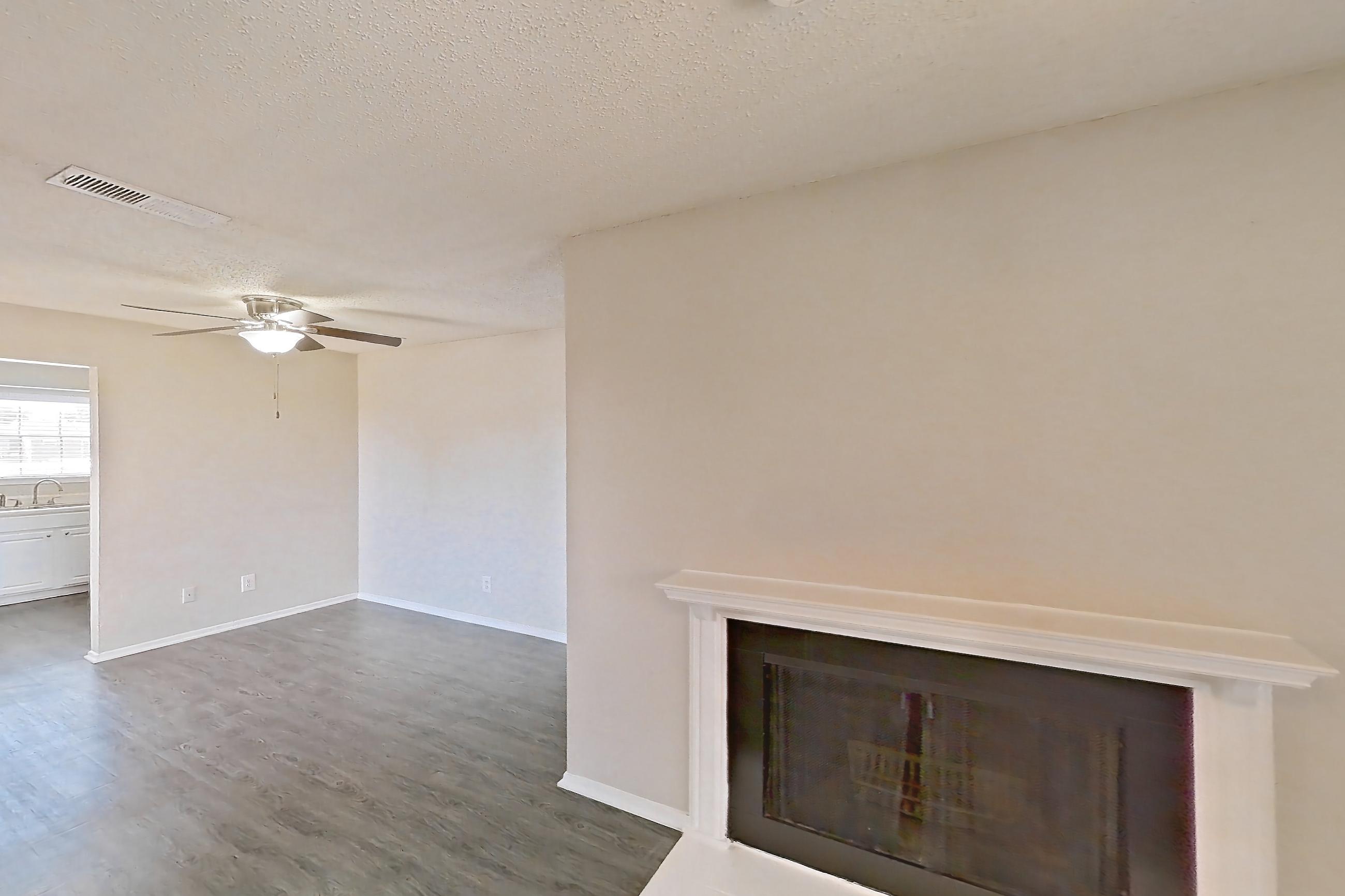 Living room with black appliances, dark wood-finish flooring, dishwasher, and fireplace, Apartment 2219 at Creekside Village