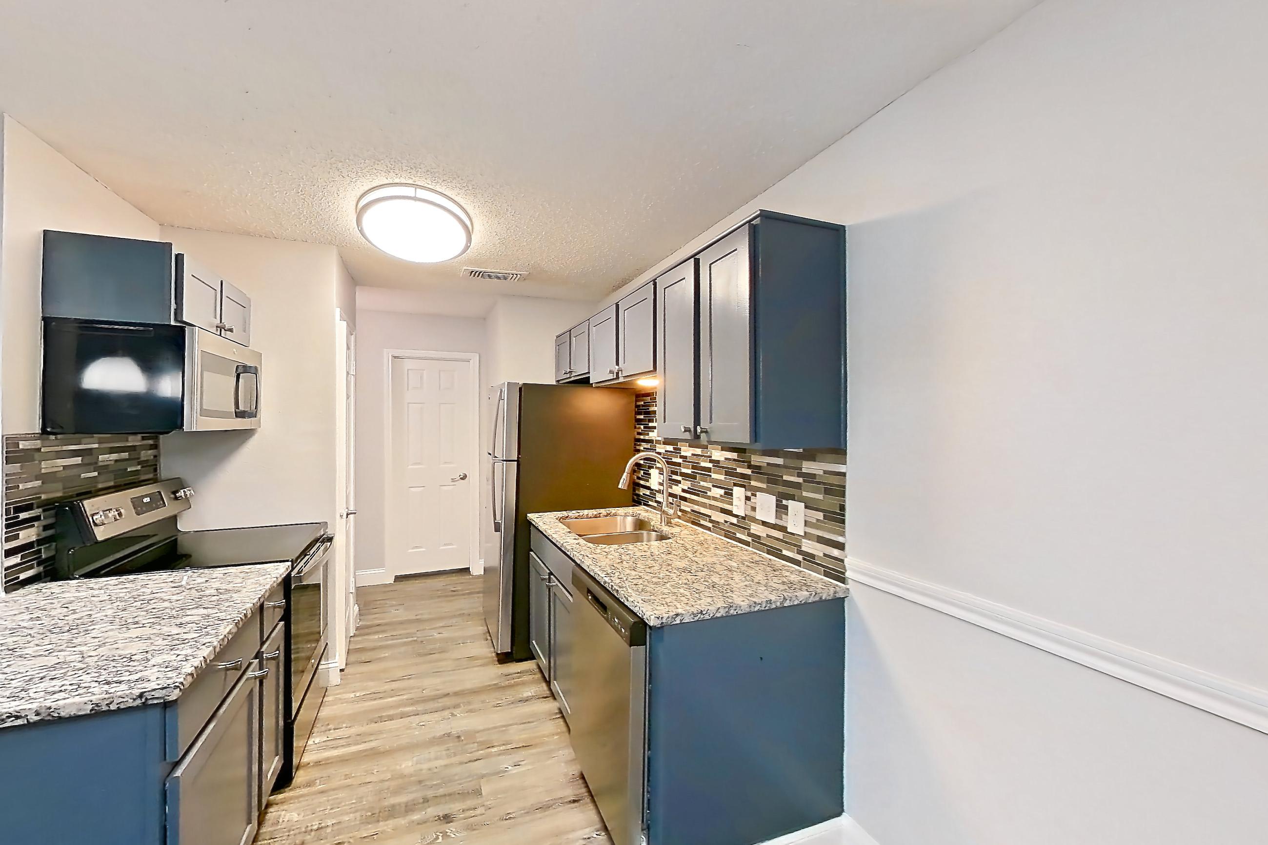 Dining room with dark wood-finish flooring, dishwasher, electric range, fireplace, light stone countertops, light wood-finish flooring, oven/range, and stainless steel appliances, Apartment 811 at Quail Ridge Apartments