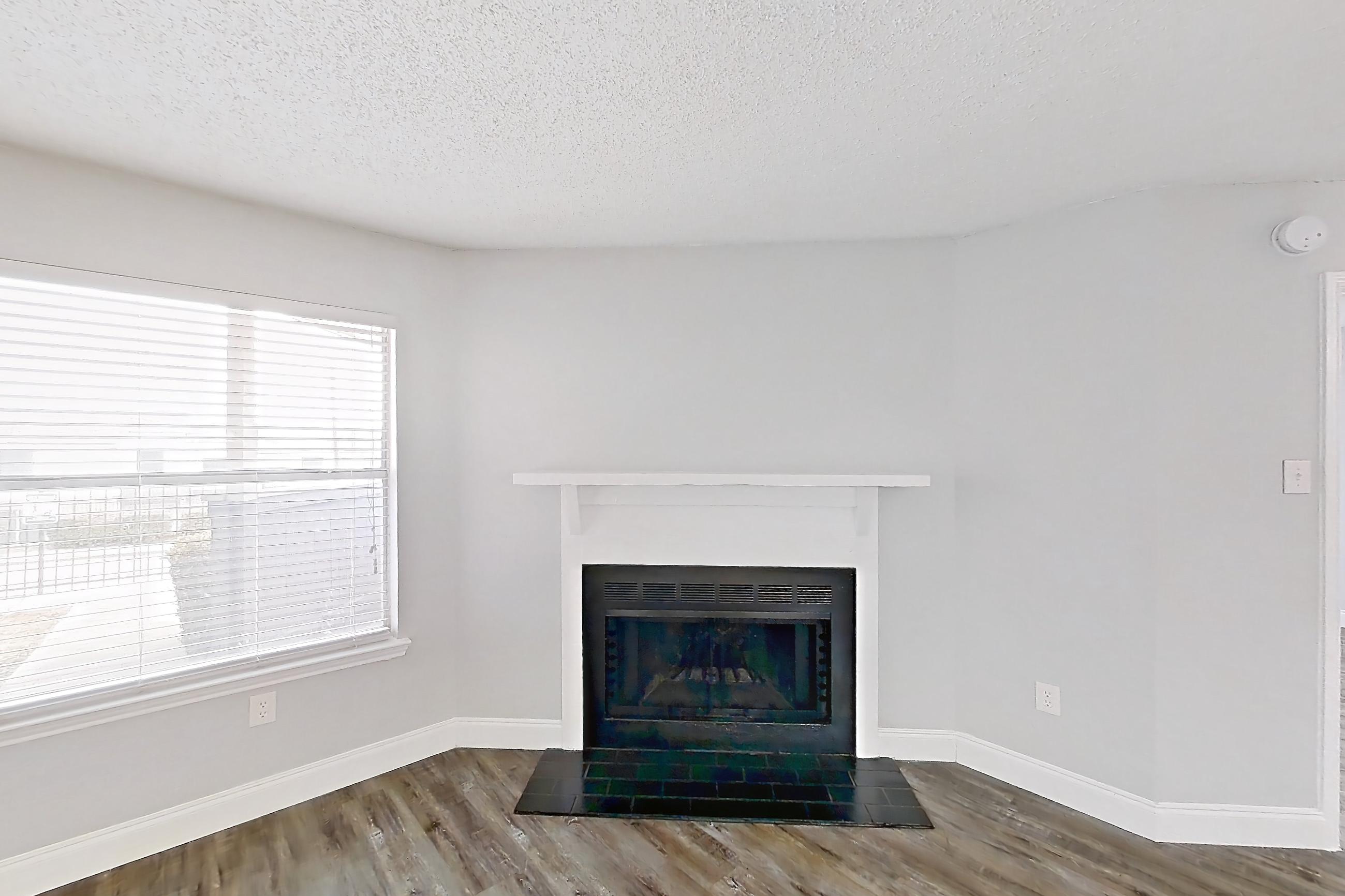 Living room with dark wood-finish flooring, fireplace, and light stone countertops, Apartment 811 at Quail Ridge Apartments
