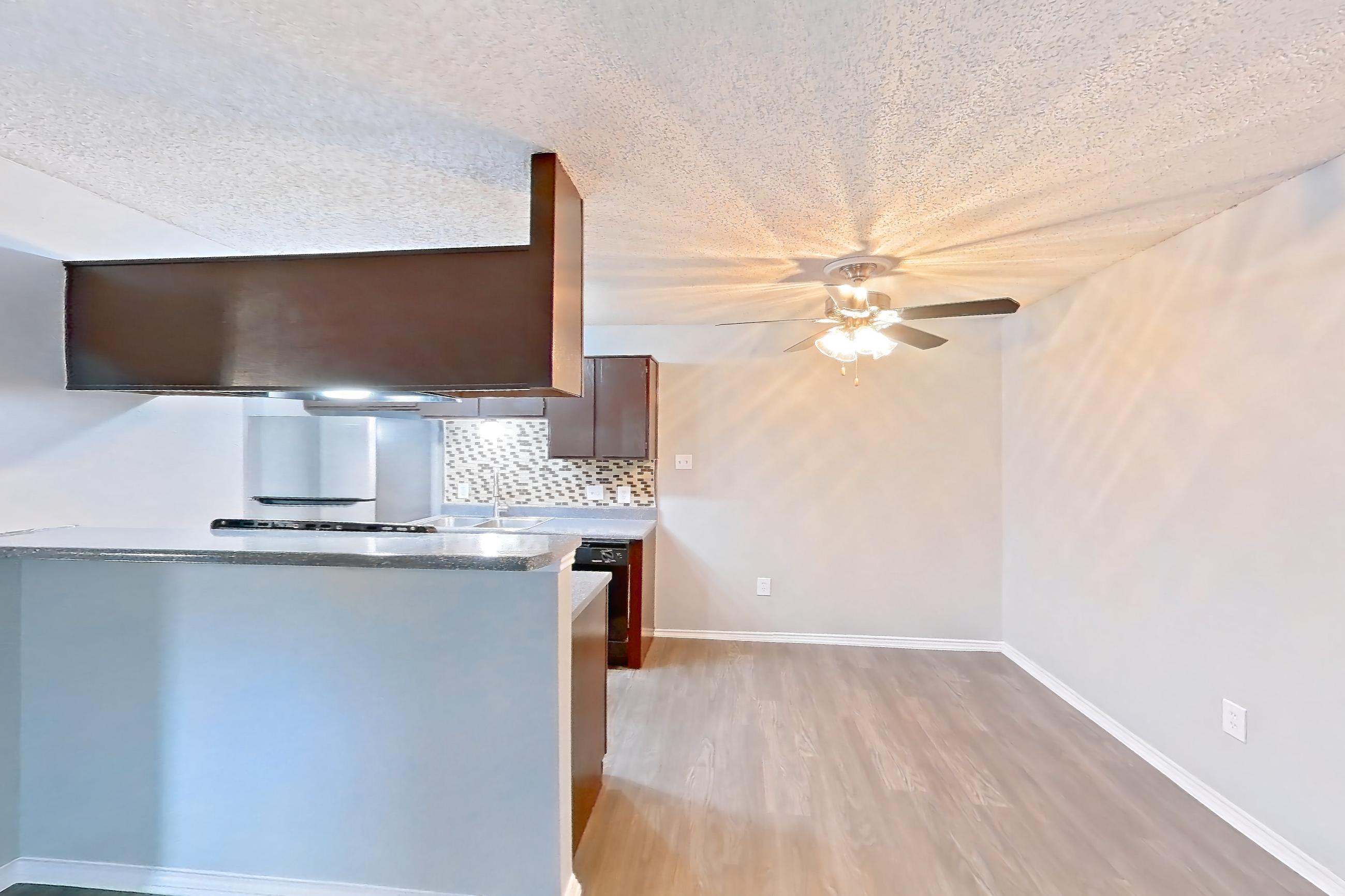 Living room with dark wood-finish flooring, fireplace, light countertops, and light wood-finish flooring, Apartment 2105 at Quail Ridge Apartments