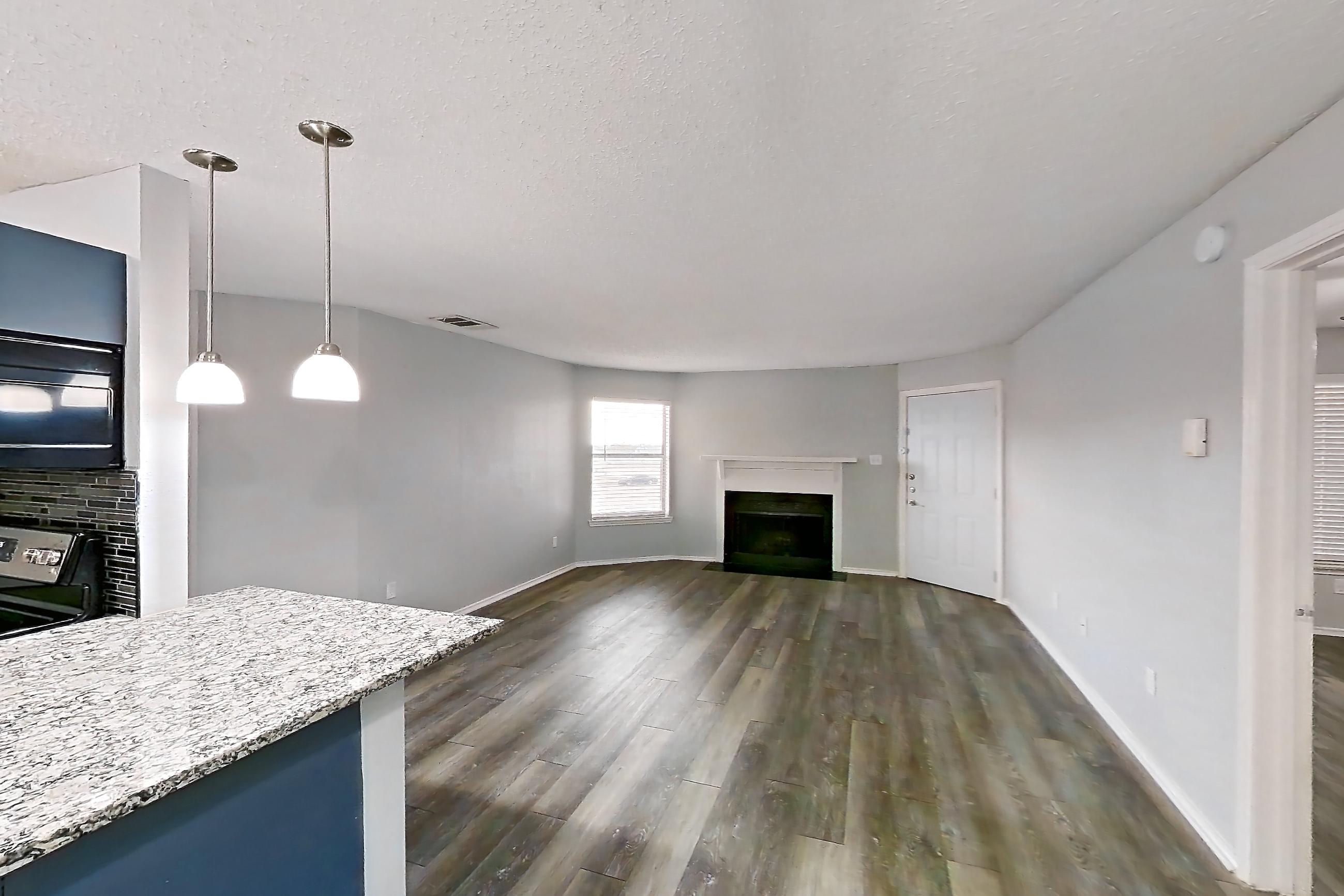 Dining room with dark wood-finish flooring, dishwasher, electric range, fireplace, light countertops, light stone countertops, light wood-finish flooring, oven/range, refrigerator, and stainless steel appliances, Apartment 2302 at Quail Ridge Apartments