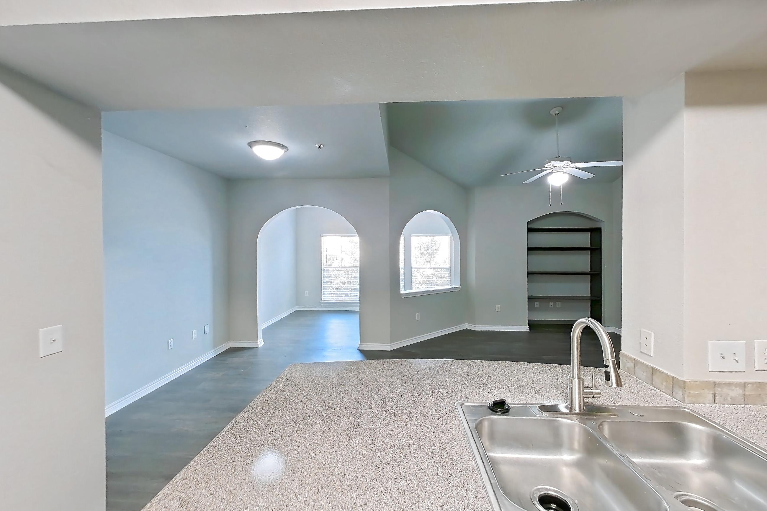 Kitchen with dishwasher, electric range, light countertops, light stone countertops, light wood-finish flooring, oven/range, refrigerator, stainless steel appliances, and white appliances, Apartment 0232 at Residences at River Park West