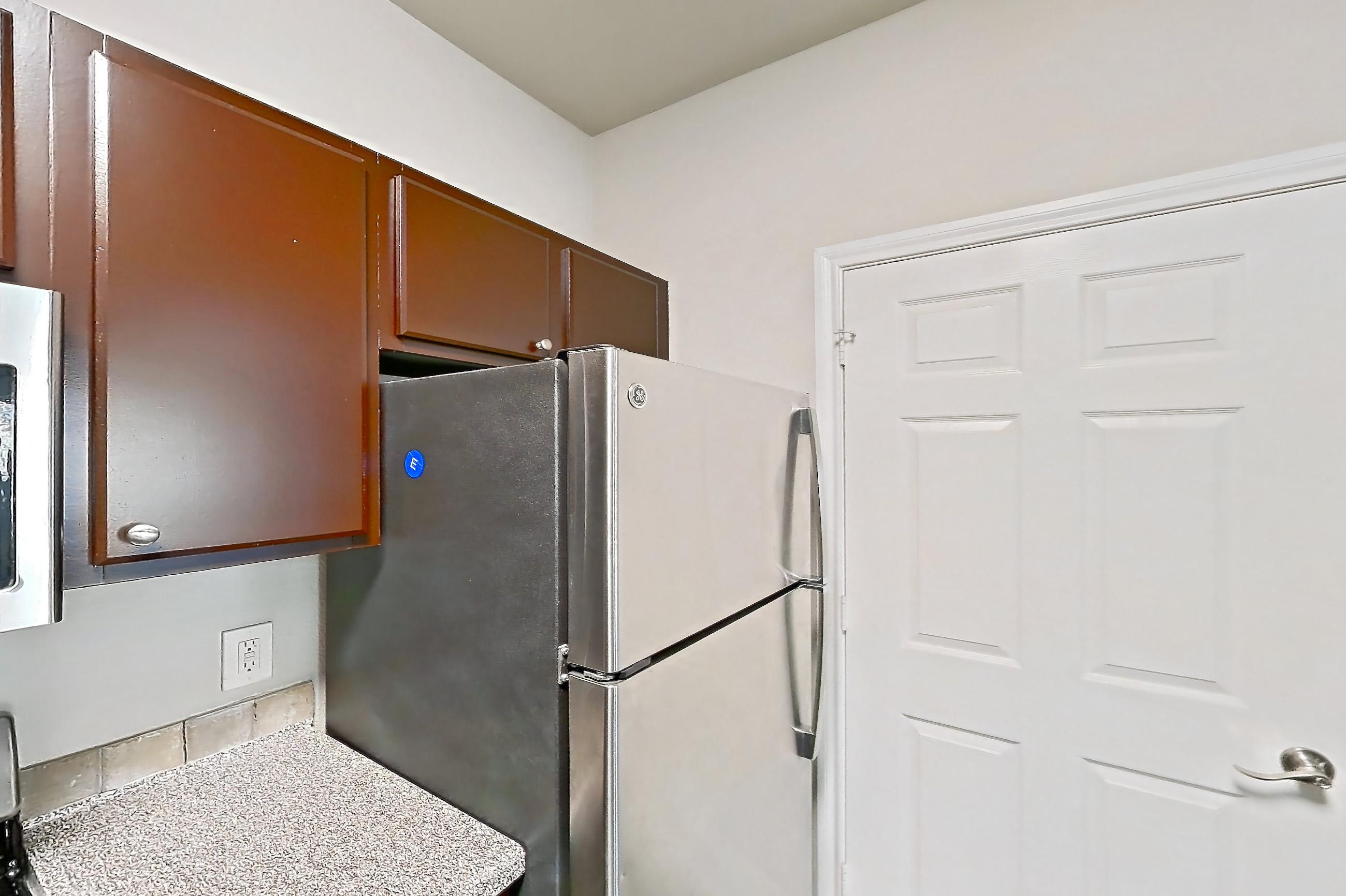 Kitchen with dishwasher, electric range, light countertops, light stone countertops, light wood-finish flooring, oven/range, refrigerator, stainless steel appliances, and white appliances, Apartment 0232 at Residences at River Park West