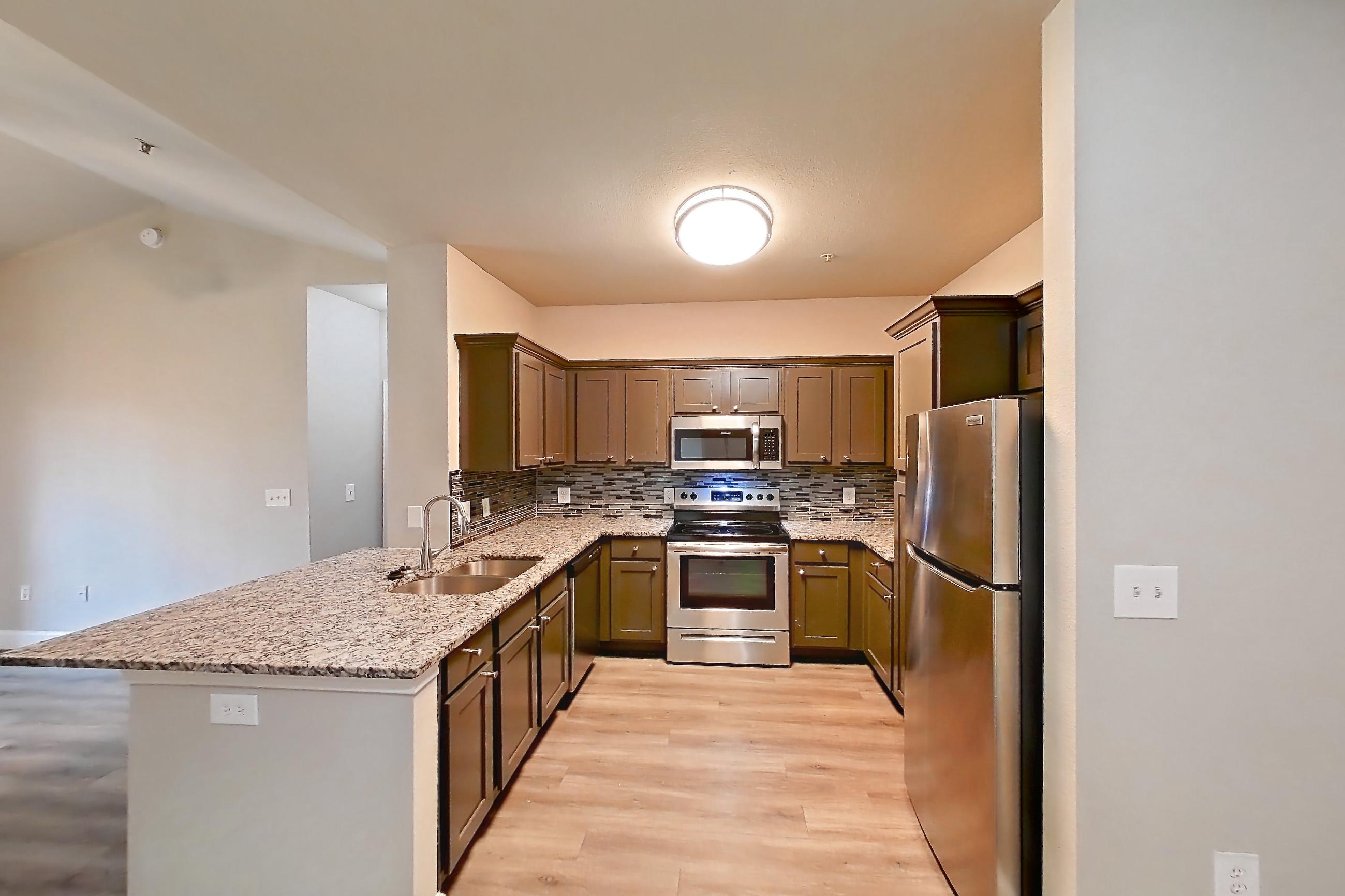 Dining room with electric range, light countertops, light stone countertops, light wood-finish flooring, oven/range, refrigerator, and stainless steel appliances, Apartment 1532 at Residences at River Park West