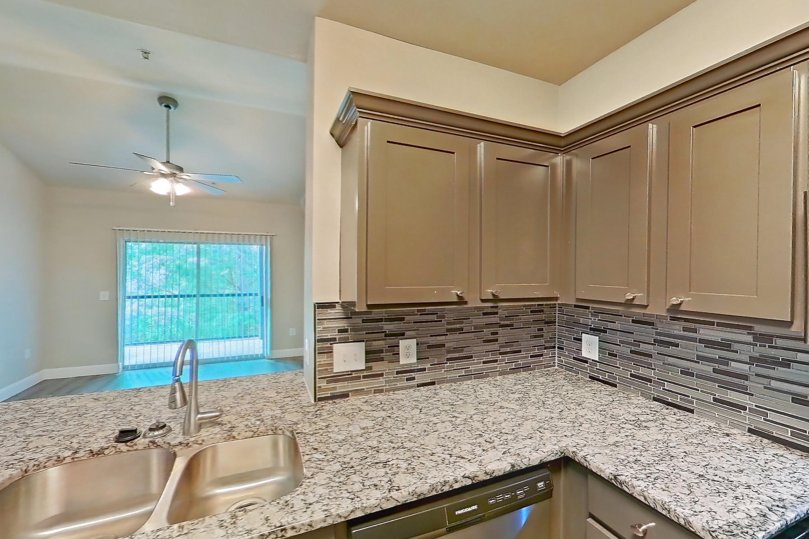 Kitchen with dishwasher, light stone countertops, light wood-finish flooring, oven/range, refrigerator, and stainless steel appliances, Apartment 1532 at Residences at River Park West