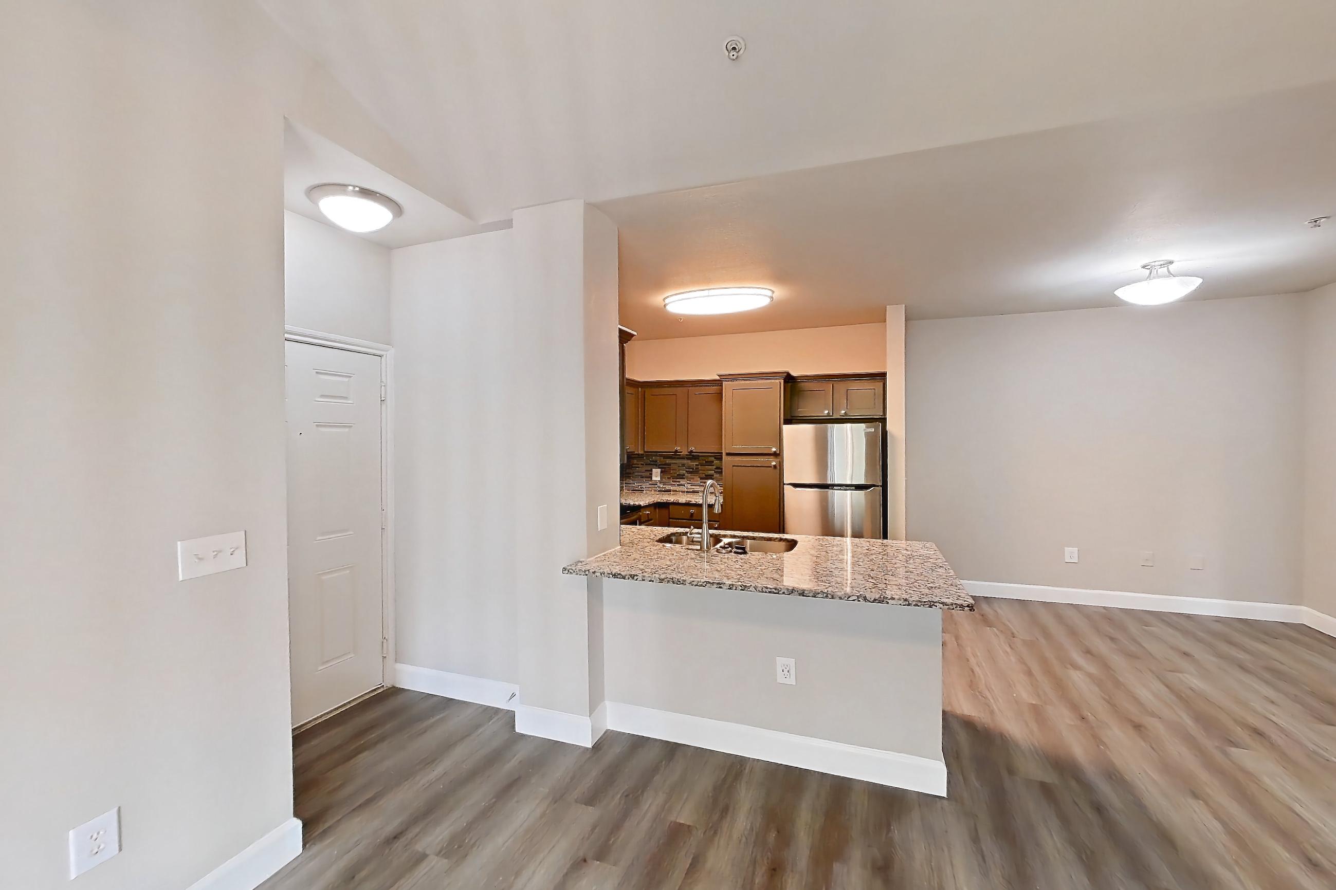 Living room with light stone countertops, light wood-finish flooring, refrigerator, and stainless steel appliances, Apartment 1532 at Residences at River Park West
