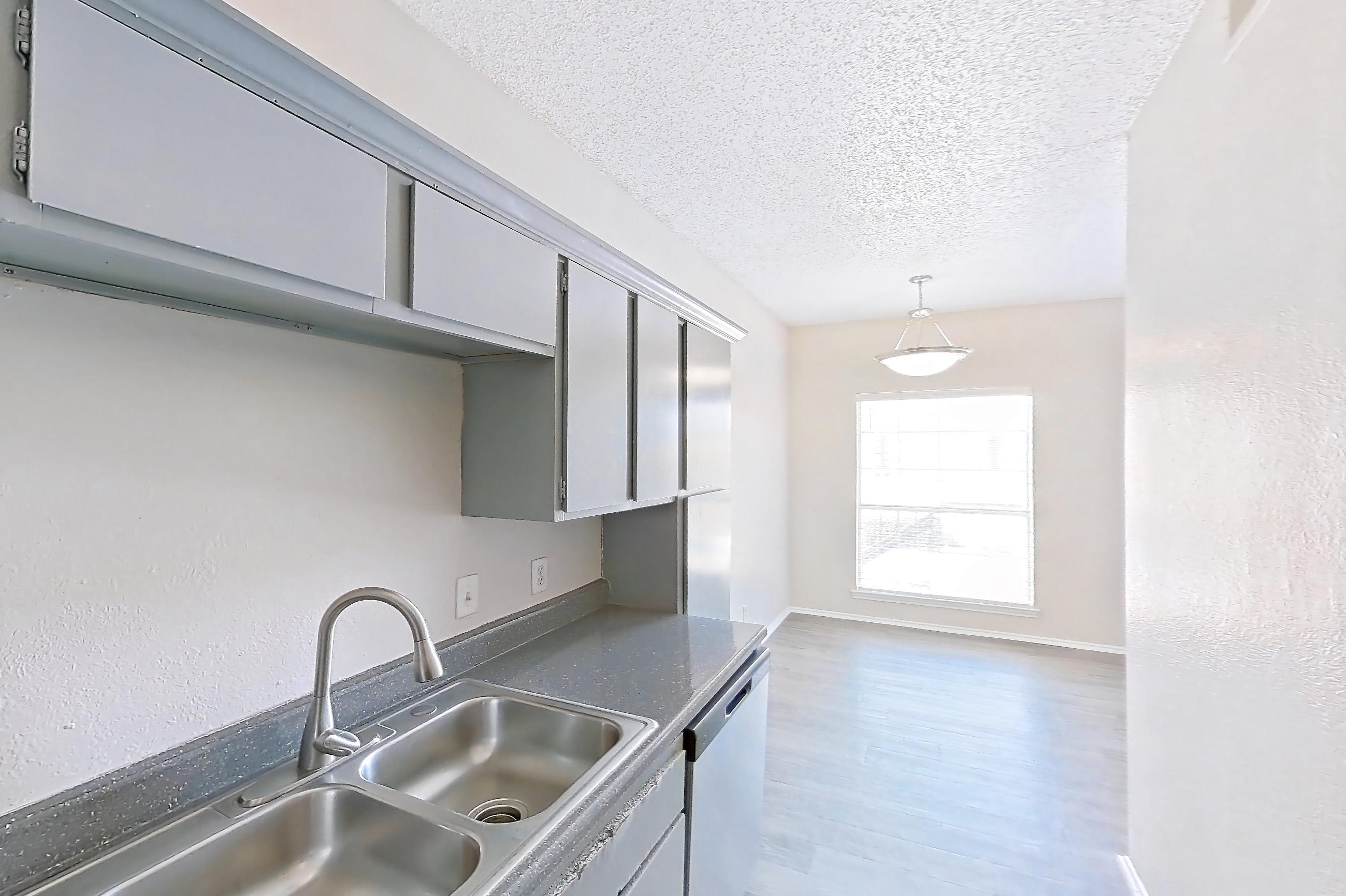 Kitchen with dark countertops, dishwasher, electric range, light wood-finish flooring, microwave, oven/range, refrigerator, stainless steel appliances, and white appliances, Apartment 0123 at Waterford on the Meadow