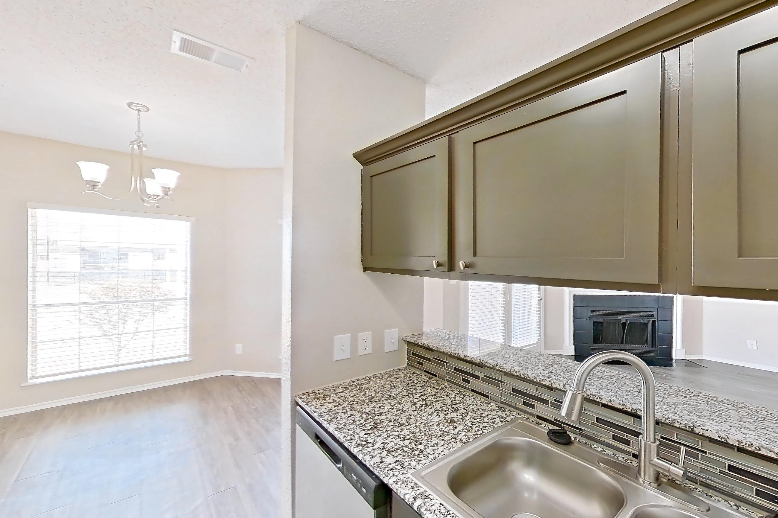 Kitchen with dishwasher, light countertops, light stone countertops, light wood-finish flooring, refrigerator, and stainless steel appliances, Apartment 1522 at Waterford on the Meadow